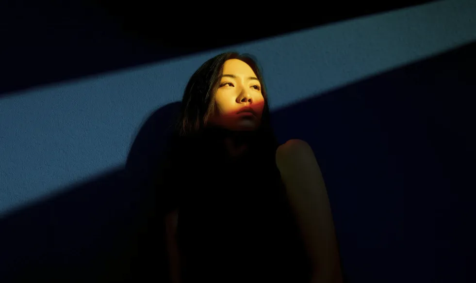 A beam of light shines upon the Asian girl.