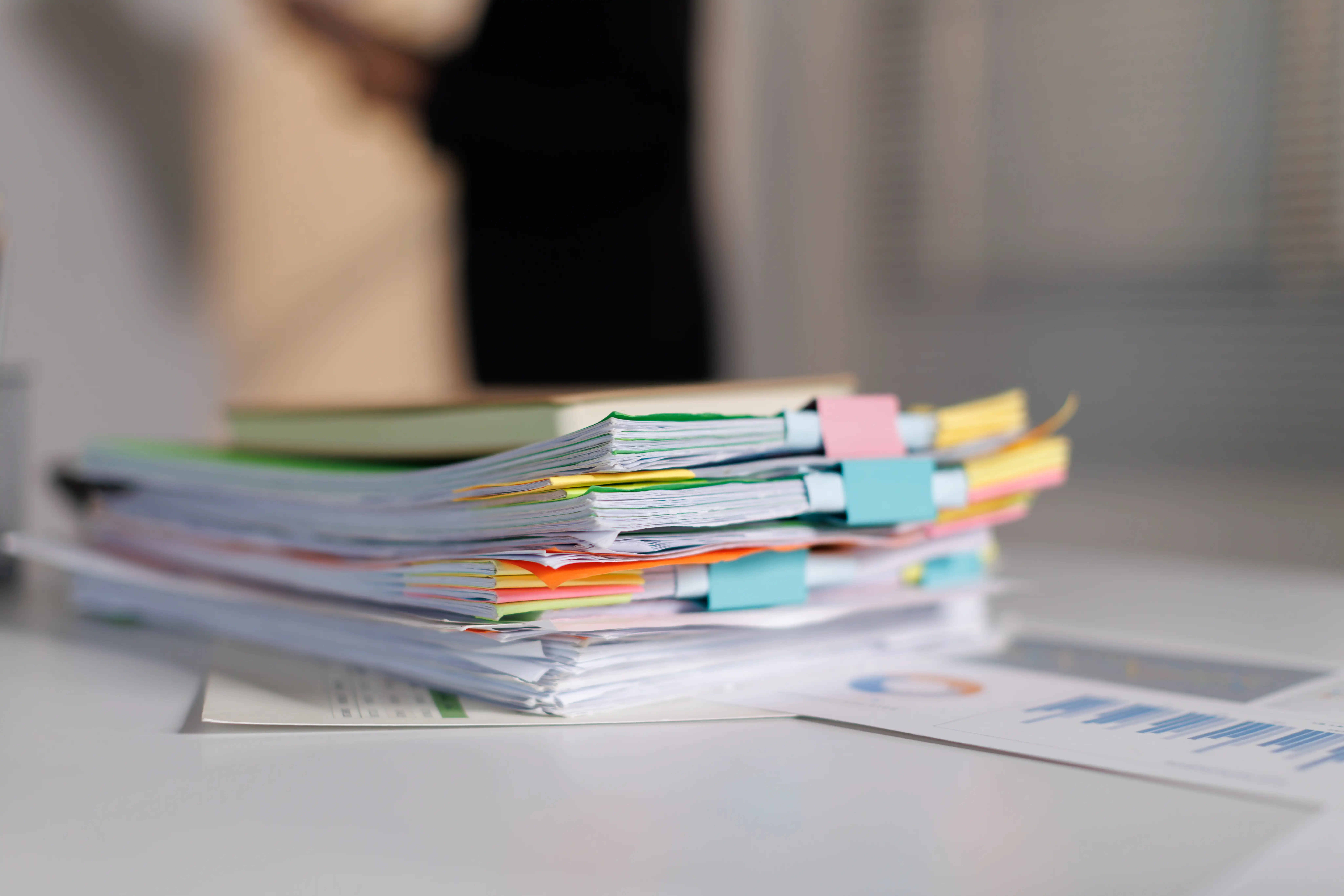 Large stack of organized employment documents with colorful sticky tabs, representing key evidence to gather for a California job relocation fraud claim