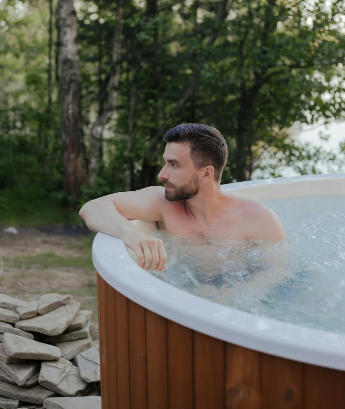 Homme relaxant dans un jacuzzi extérieur en pleine nature.