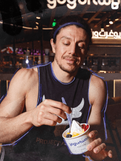 A fit man eating frozen yogurt after exercising, illustrating a balance between indulgence and a healthy lifestyle.