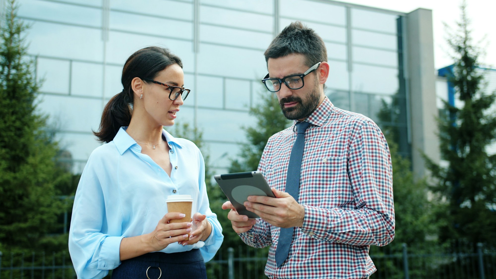 Two colleagues reviewing a report on a tablet outside an office