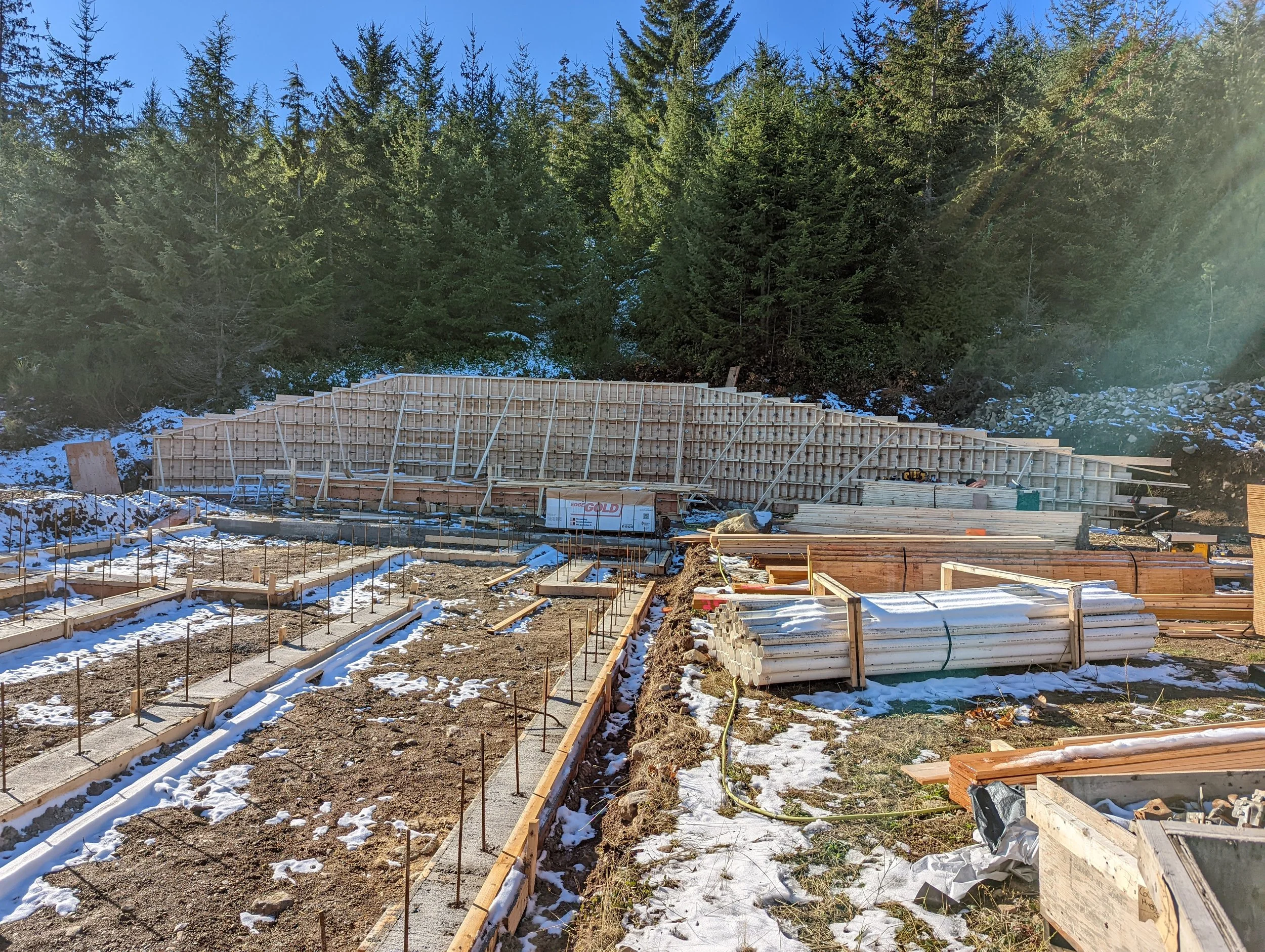 Modern two-story home with large glass windows, warmly lit interiors, and a balcony. Surrounded by trees and a manicured lawn at dusk. Cozy ambiance.