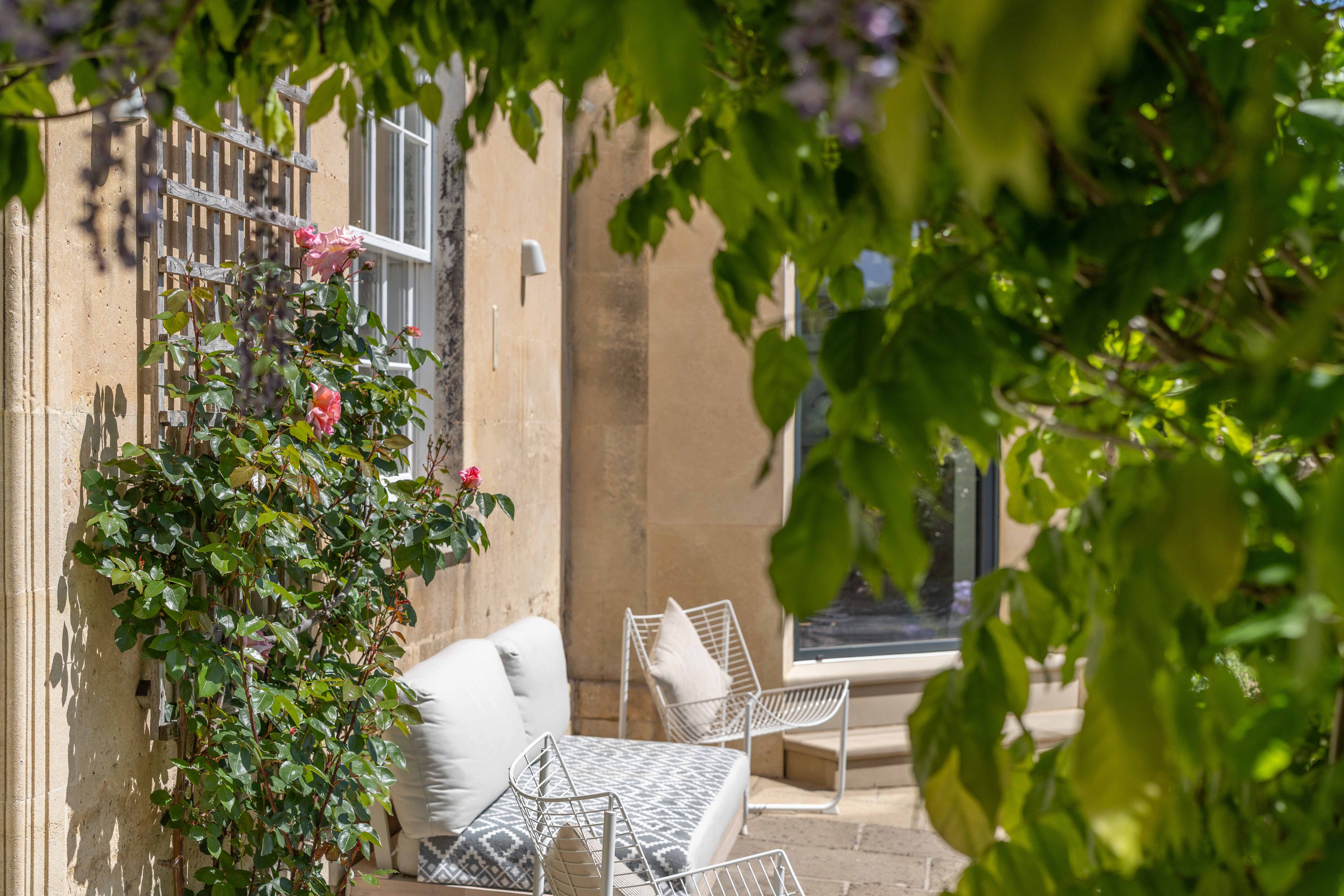 Stone terrace framed by wisteria, 1 Belcombe Place Bradford-on-Avon — exterior property photography by Captura Media