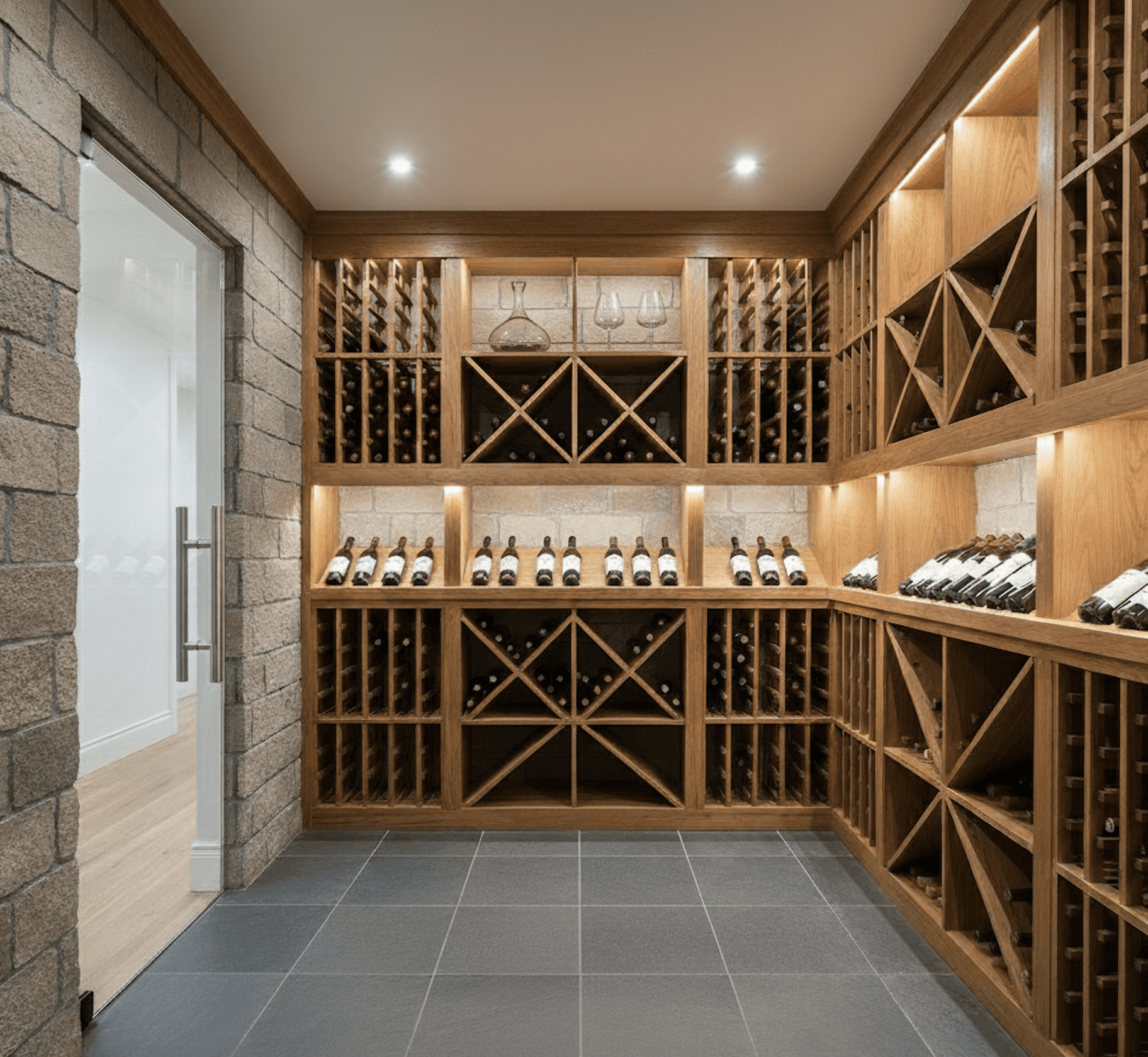Traditional-style wine cellar in Lakeway, Texas featuring natural limestone walls, solid white oak racking, and a glass entry door with polished nickel hardware, designed by Prestige Wine Cellars.