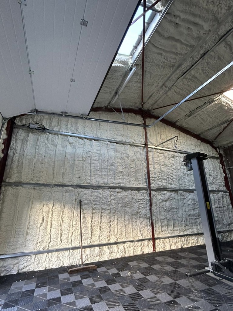 Espace garage avec murs et plafond isolés à l'aide de mousse de polyuréthane projetée, améliorant l'efficacité thermique.