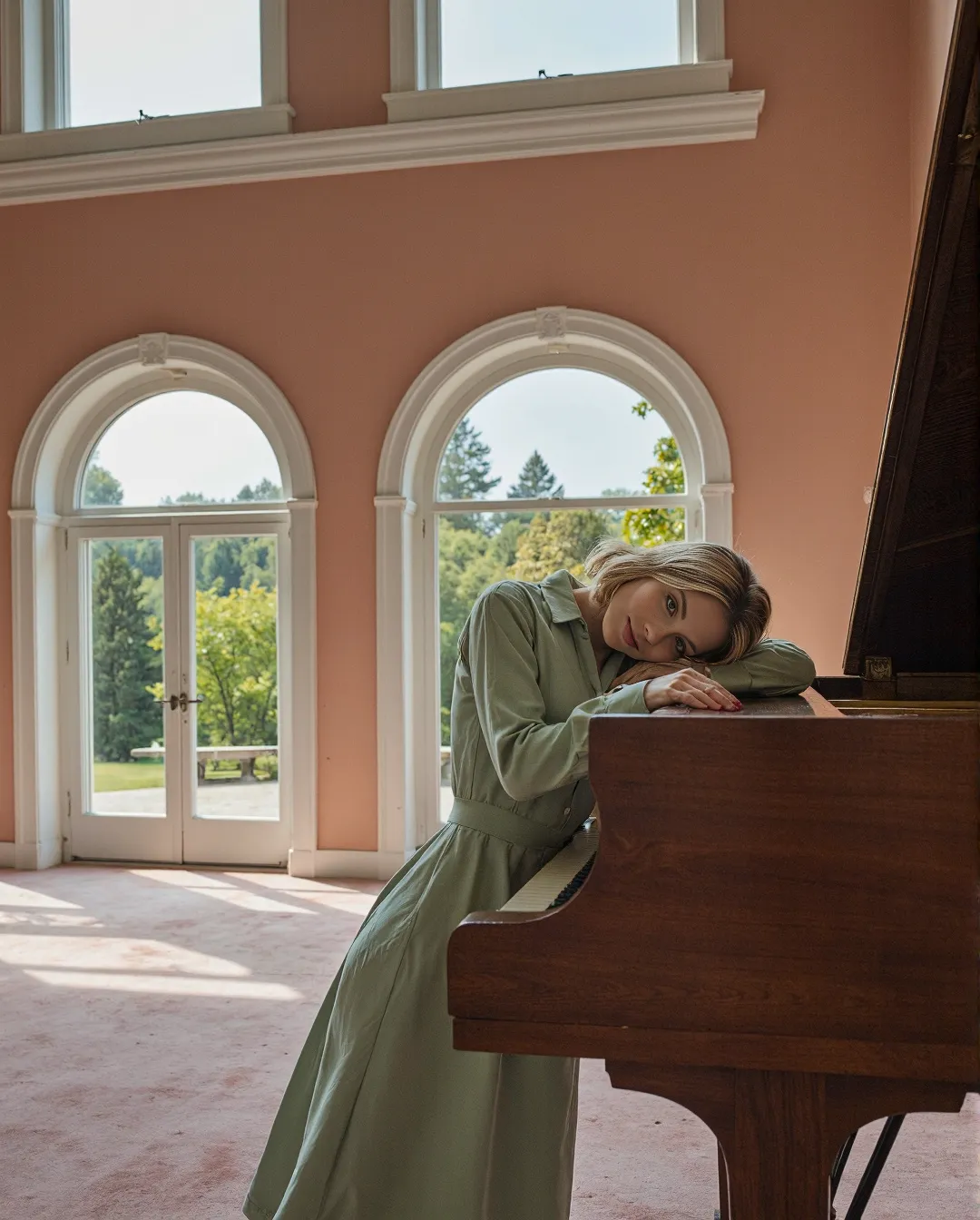 A serene musical moment in a blush-pink room with arched windows, featuring a wooden piano and soft natural light filtering through.