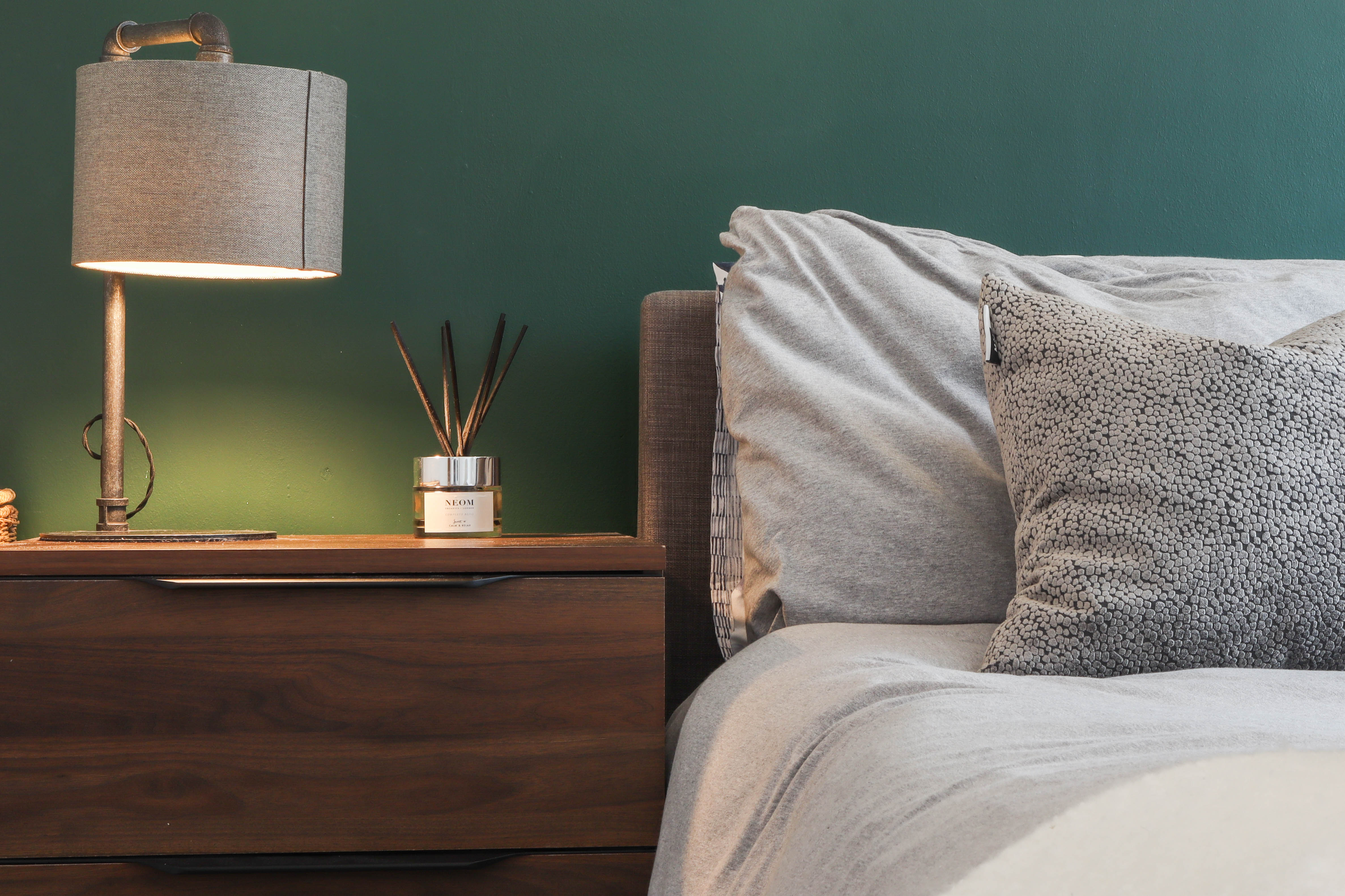 Mordern Airbnb photography with a grey double bed and green wall 