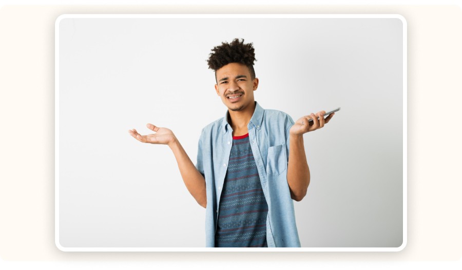 Confused man shrugging while holding smartphone, expressing uncertainty or doubt