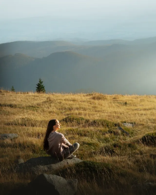Woman sitting in an open field at golden hour