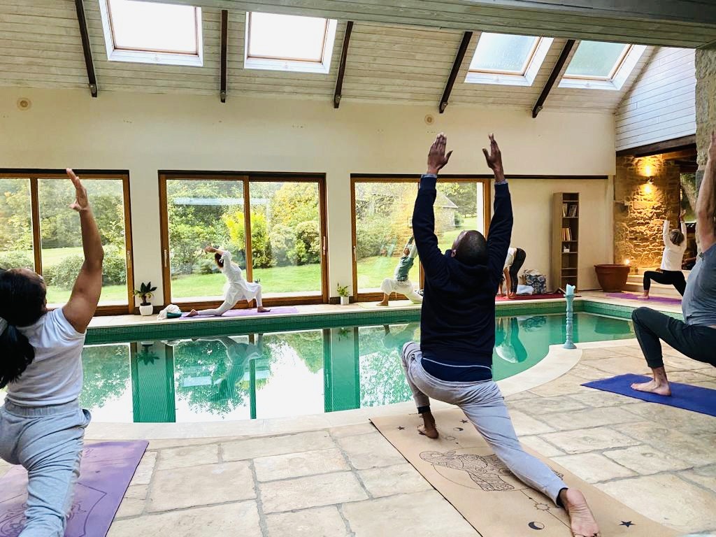 Plusieurs personnes en train de faire du yoga autour d'une piscine.