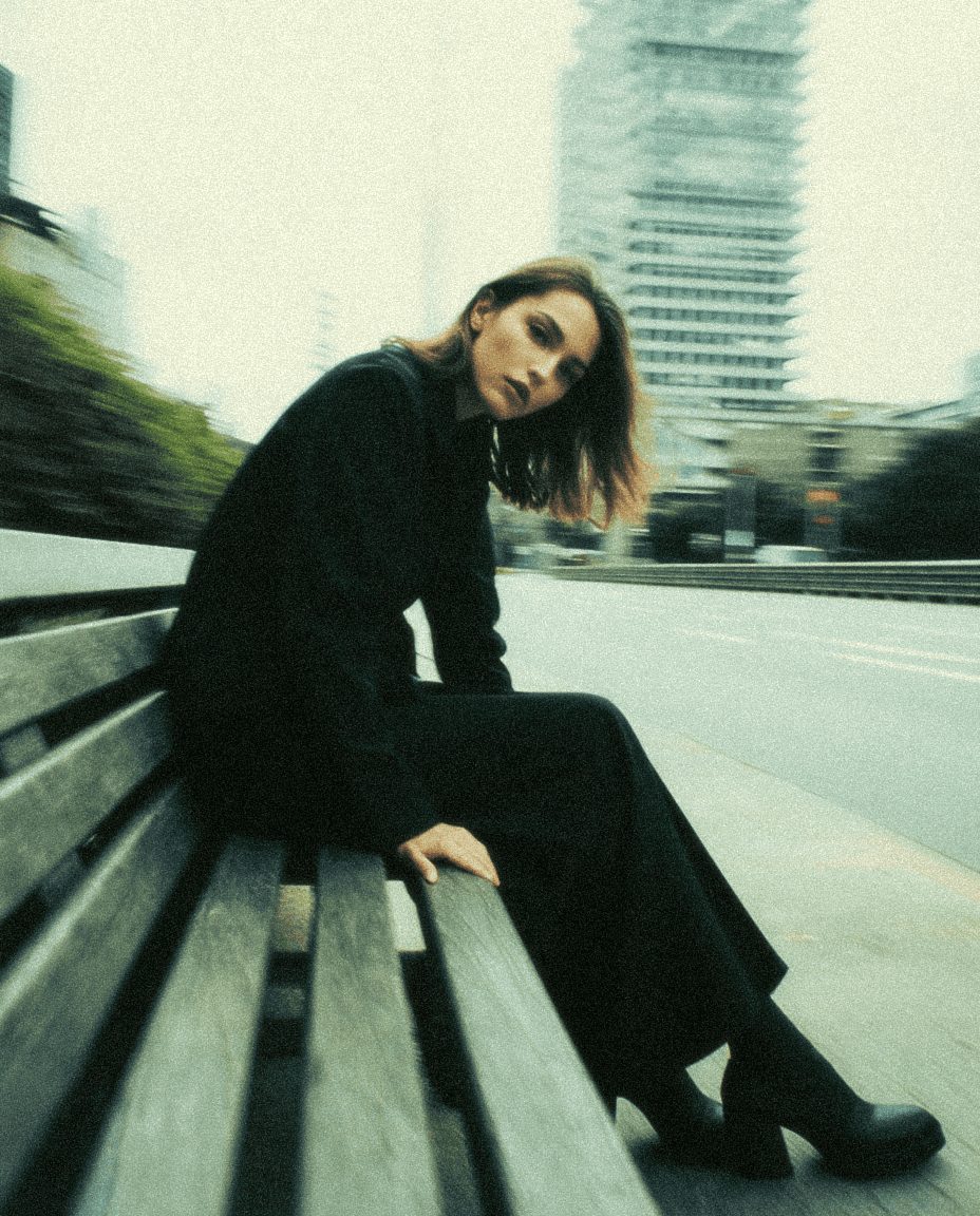 women on the street siting on a bench beside a road