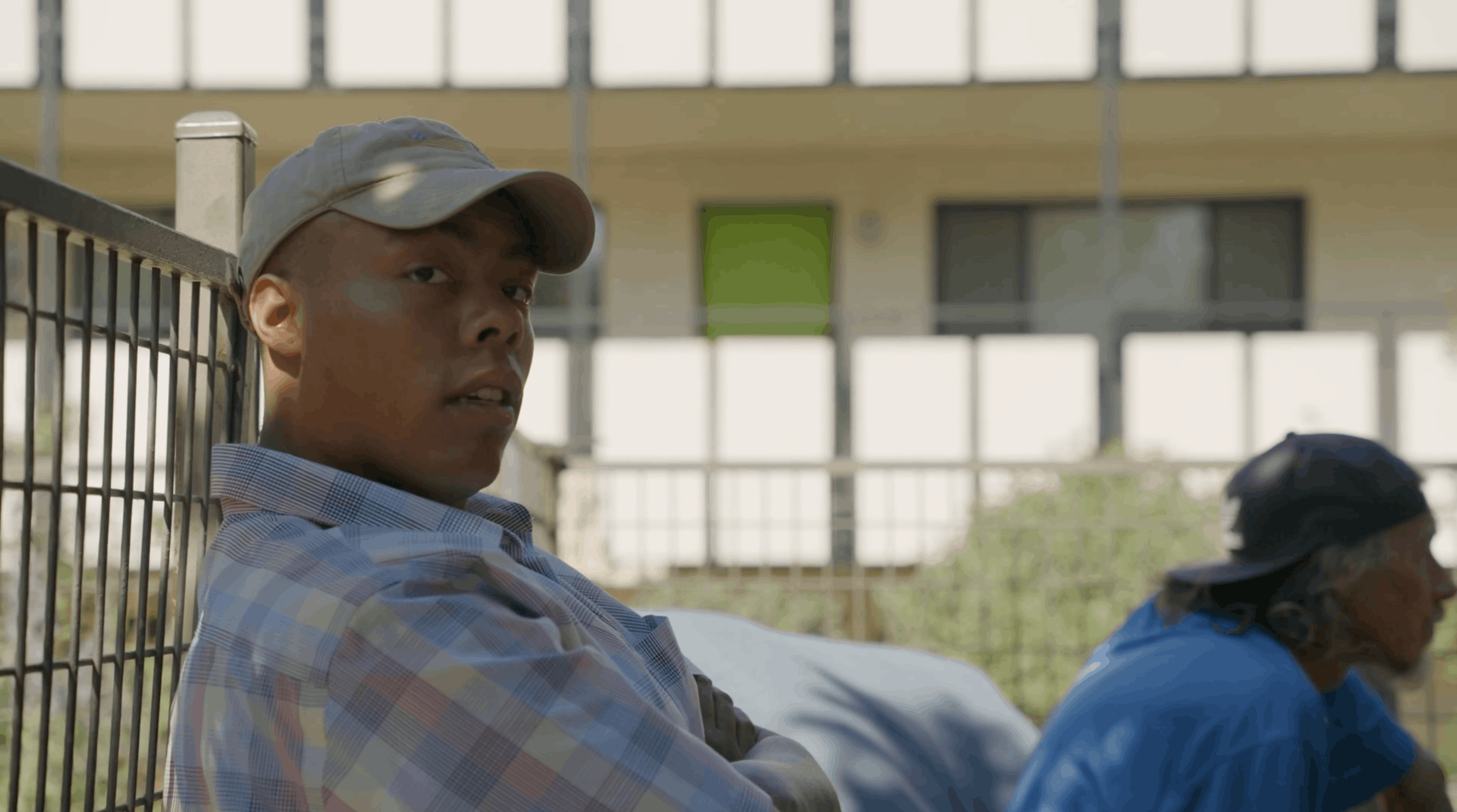 resident leaning against a fence in the courtyard at ananeo housing