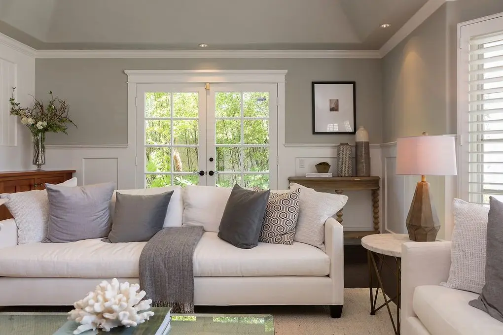 Port Streets Remodel' snug living corner with white couch, wooden console, art, and outdoor view.