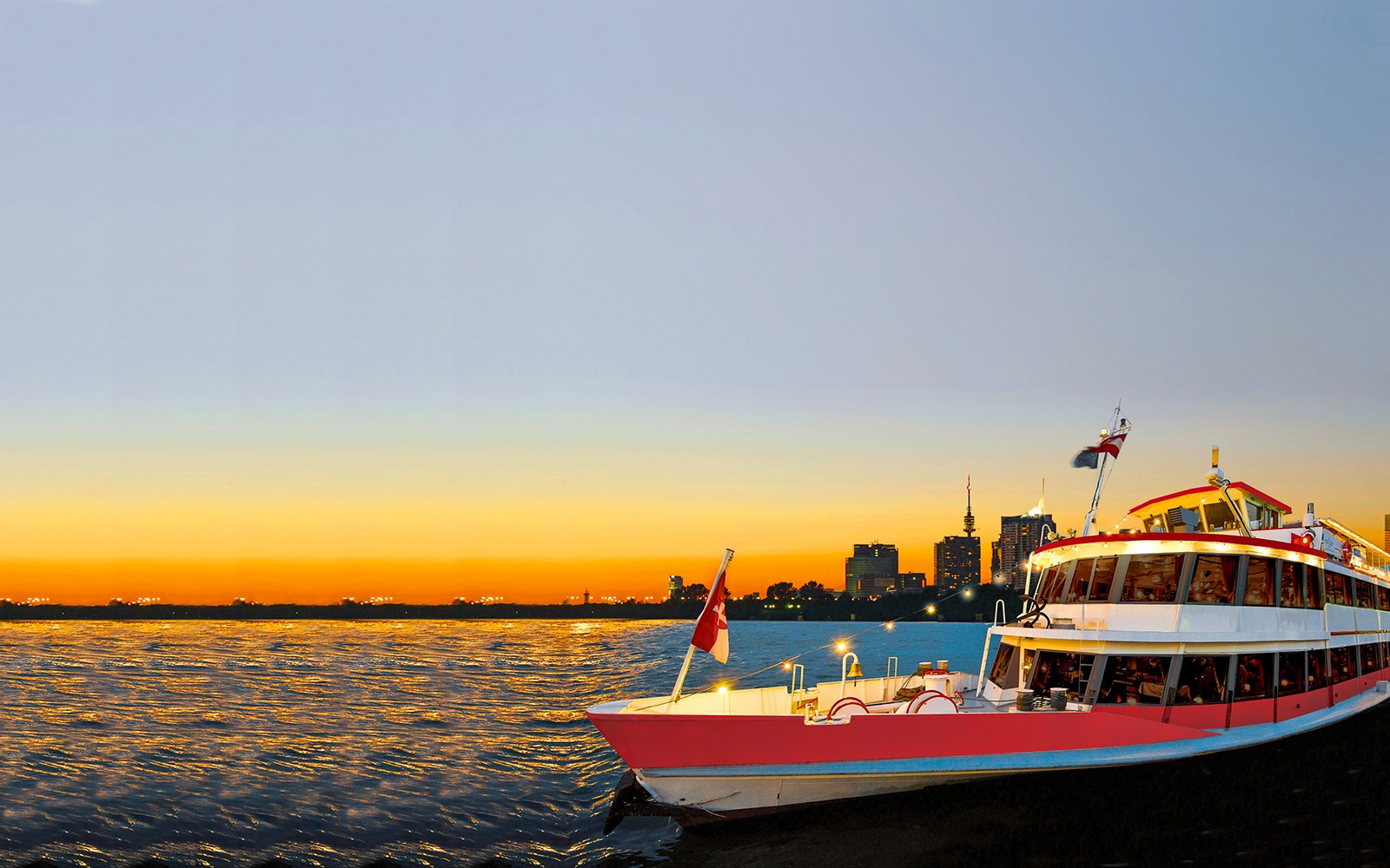 Crucero por el río Danubio al atardecer con el horizonte de la ciudad de fondo.