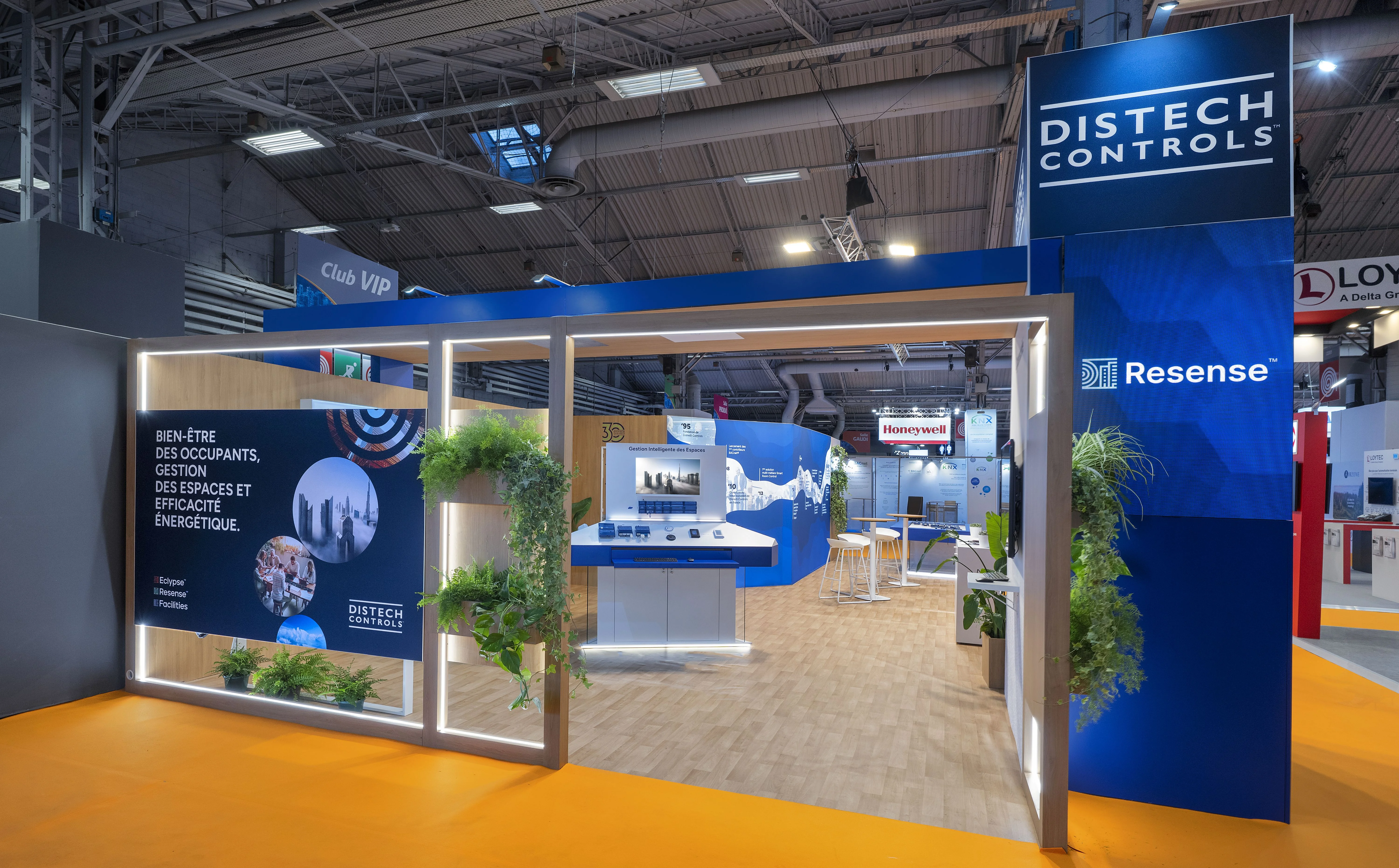 entrée du stand Distech Controls au salon IBS 2025 avec portique lumineux et végétalisation
