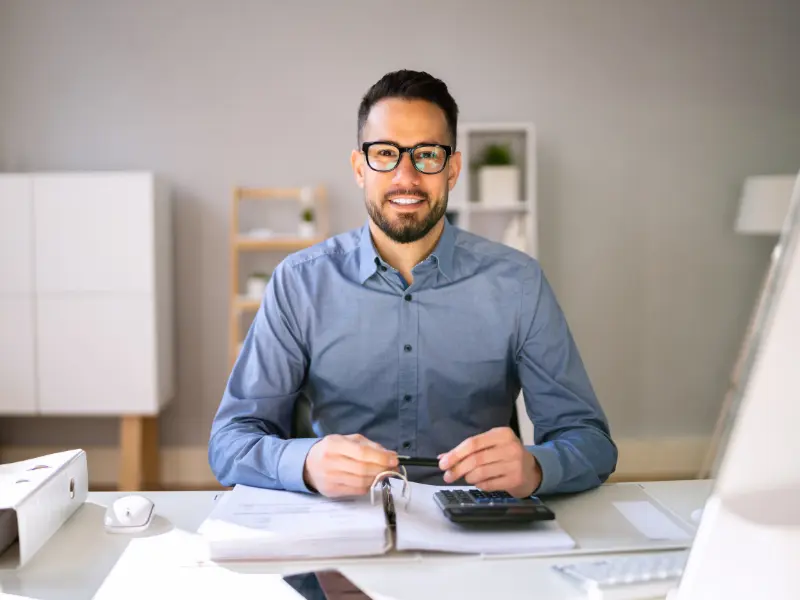 An accountant at his desk with a calculator and paperwork
