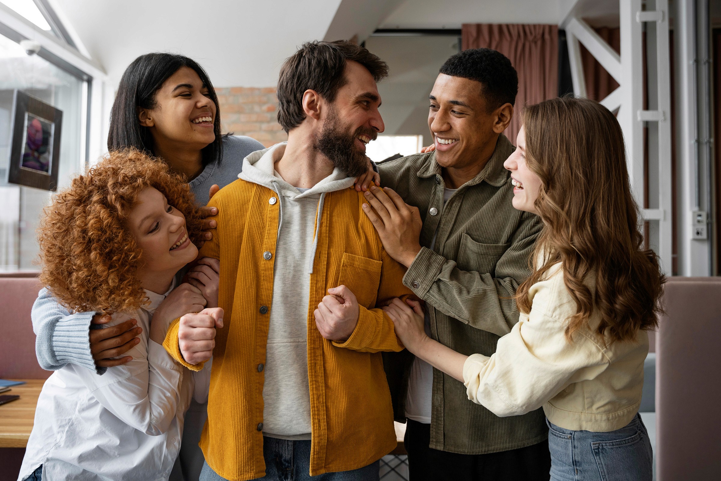 A diverse group of smiling friends or colleagues sharing a joyful moment, gathered closely in a warm and casual setting