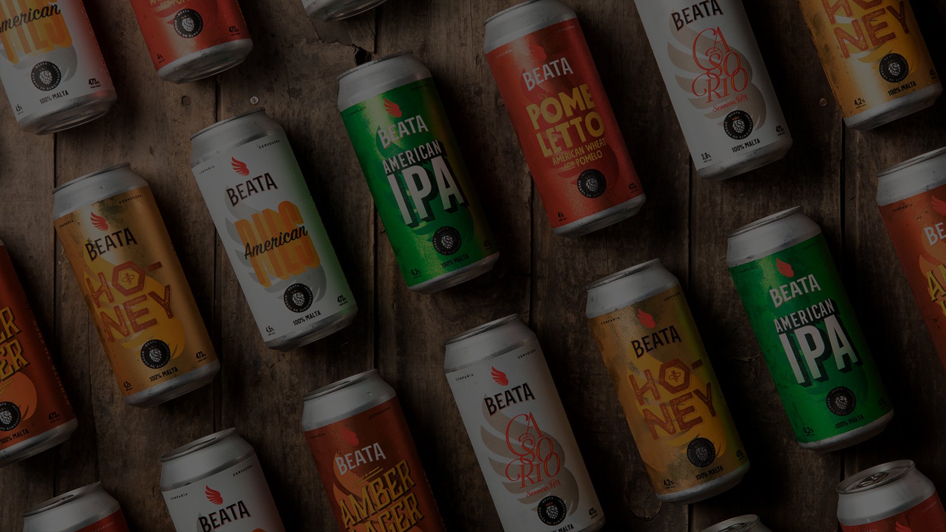 A diagonal arrangement of colorful beer cans on a wooden surface. Cans feature labels like "American IPA" and "Honey," evoking a vibrant and diverse selection.