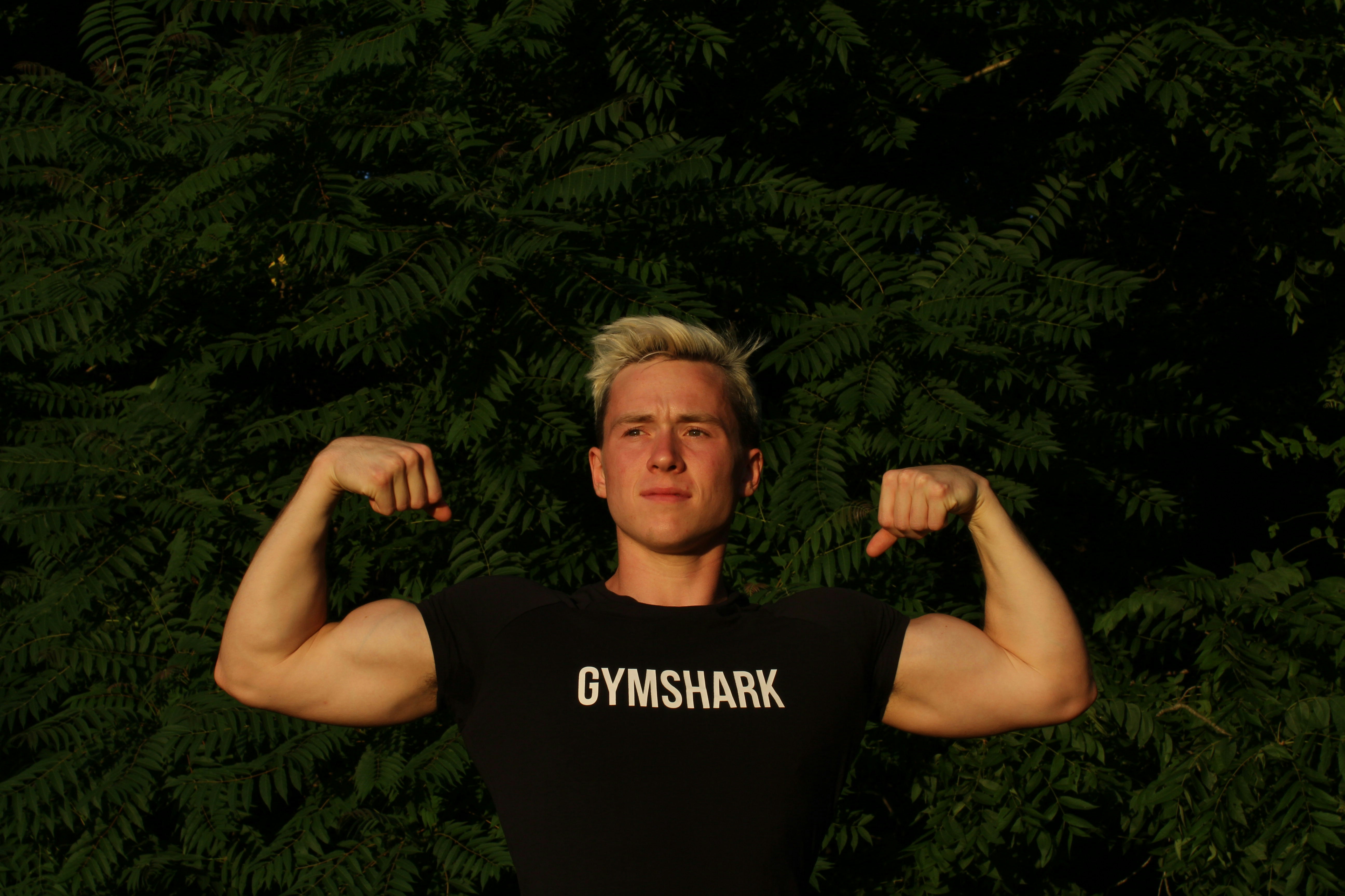 man in black tank top standing near green leaves