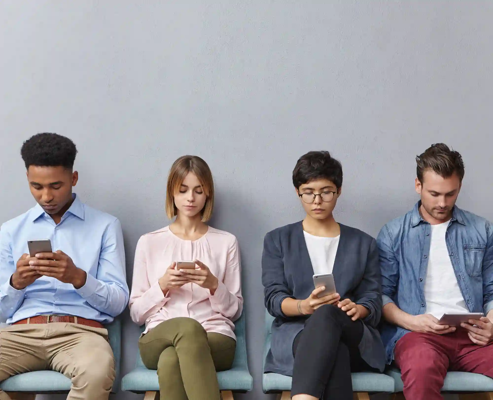 A diverse group of people sitting together while focused on their smartphones, illustrating digital engagement and social media habits.