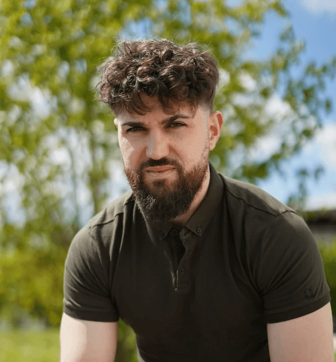 woman in sports clothes sitting and looking into the camera, holding a waterbottle.