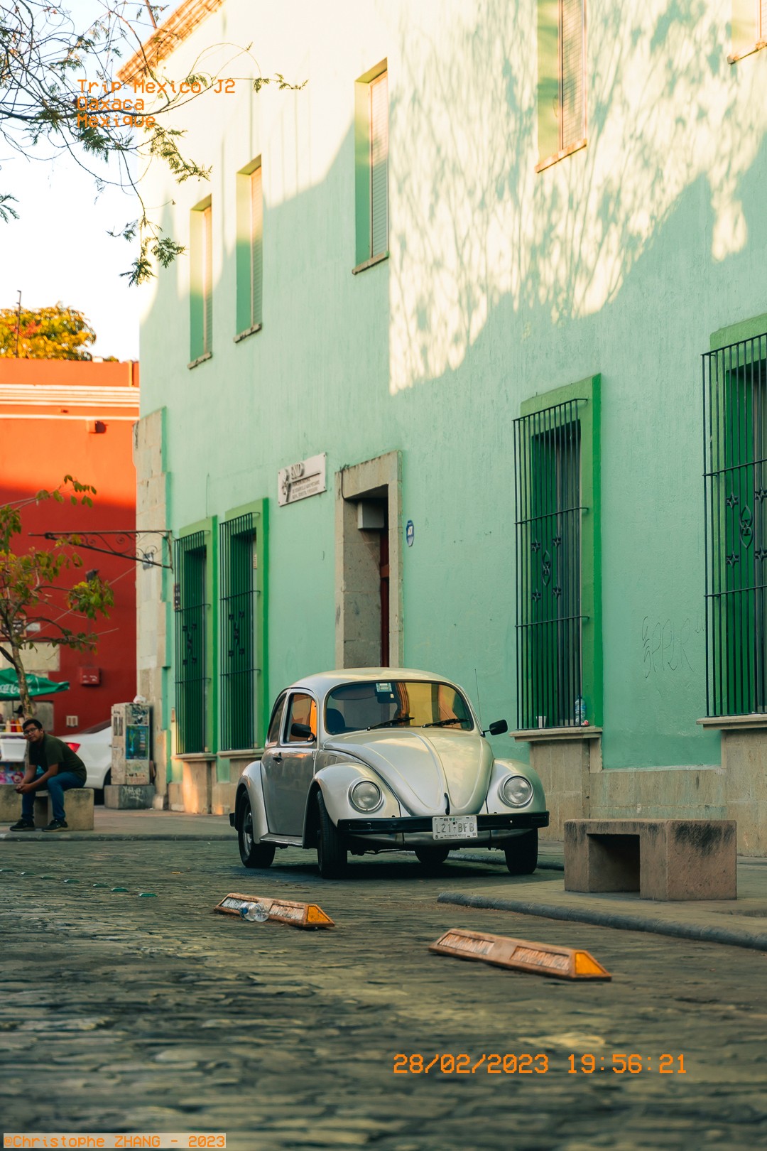 Coccinelle blanche garée devant une façade verte au centre d’Oaxaca.