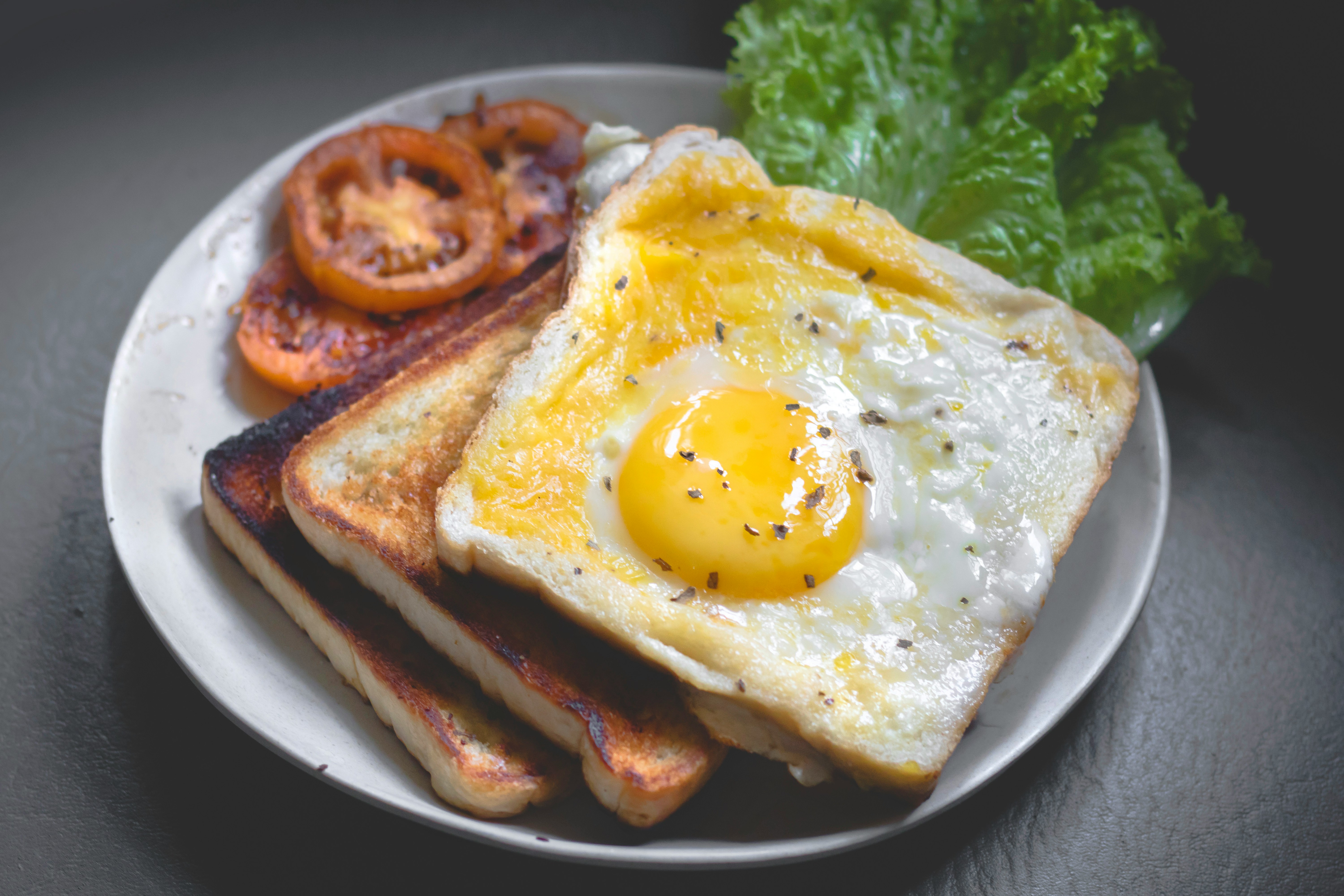 Fried egg on toast with tomatoes and lettuce on a grey plate