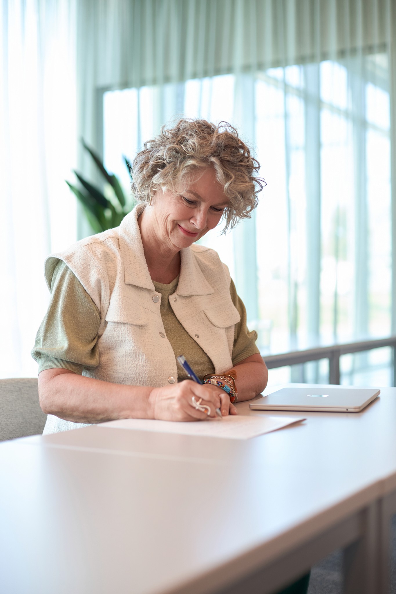 Woman writing in notebook while making eye contact with camera