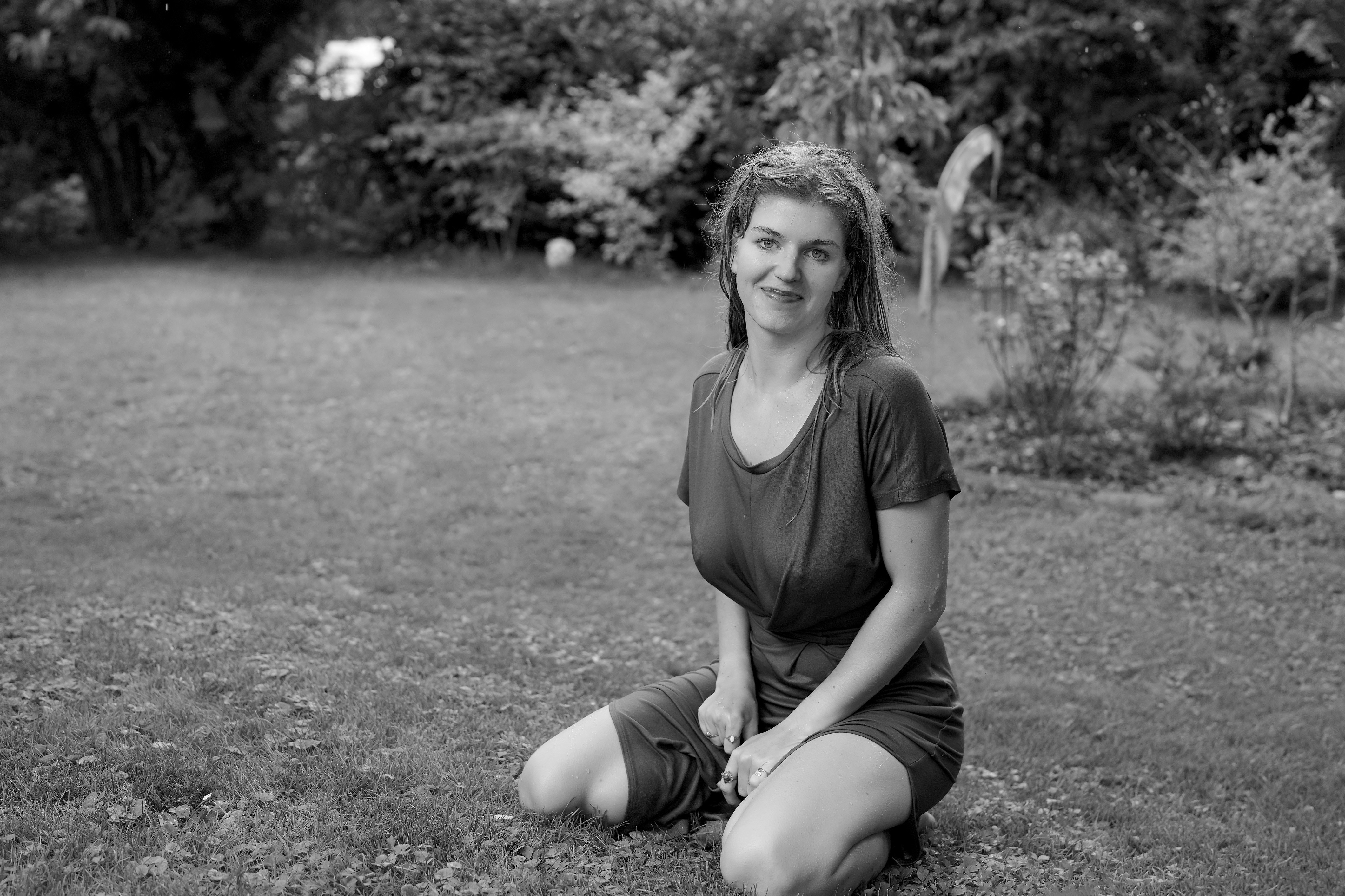 Woman poses in a garden on her knees.