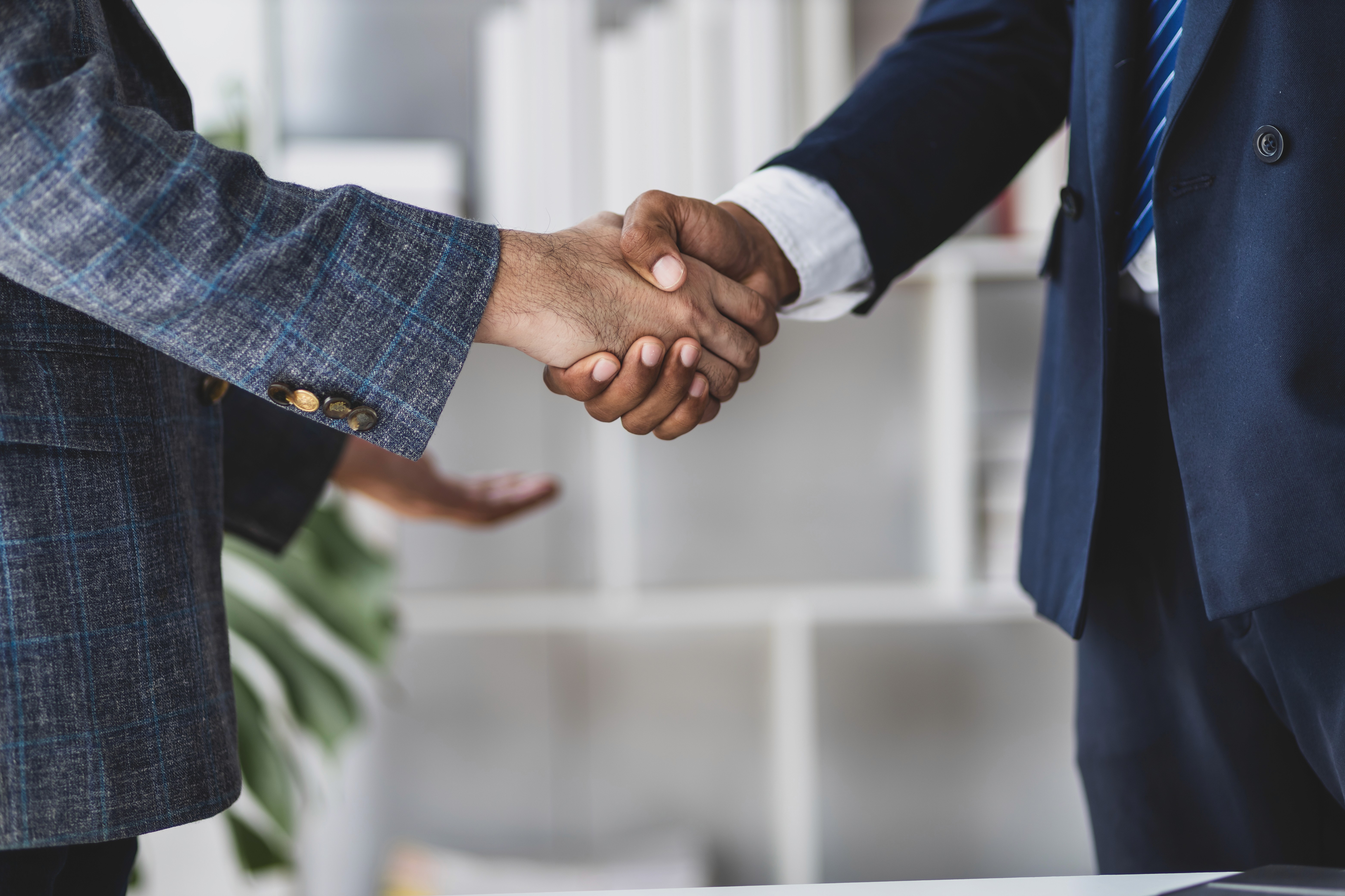 a man and a woman shaking hands in front of a laptop