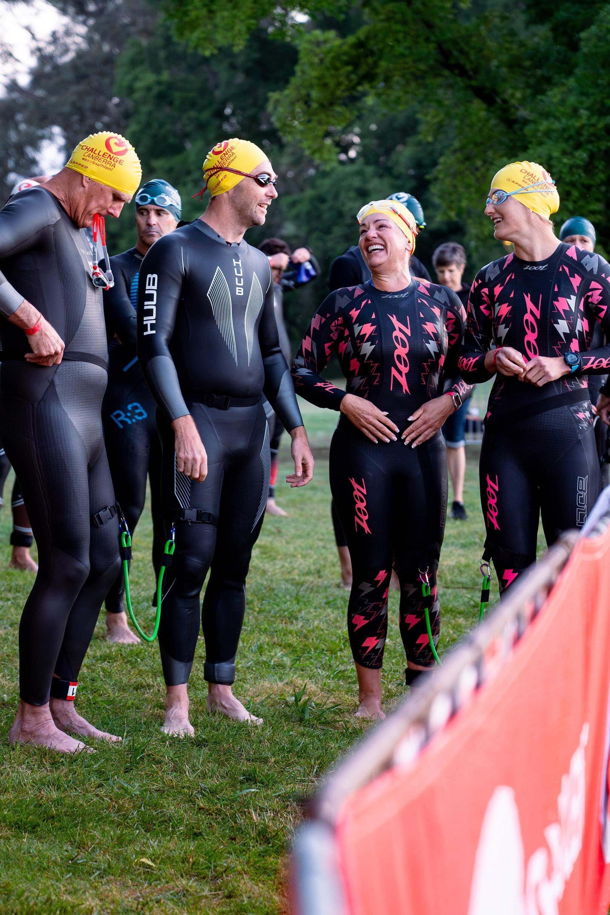 Lily lines up with her fellow para-triathlete, John, and guides Jay and Dan before the swim at the Canberra challenge. They all wear wetsuits, caps and goggles.