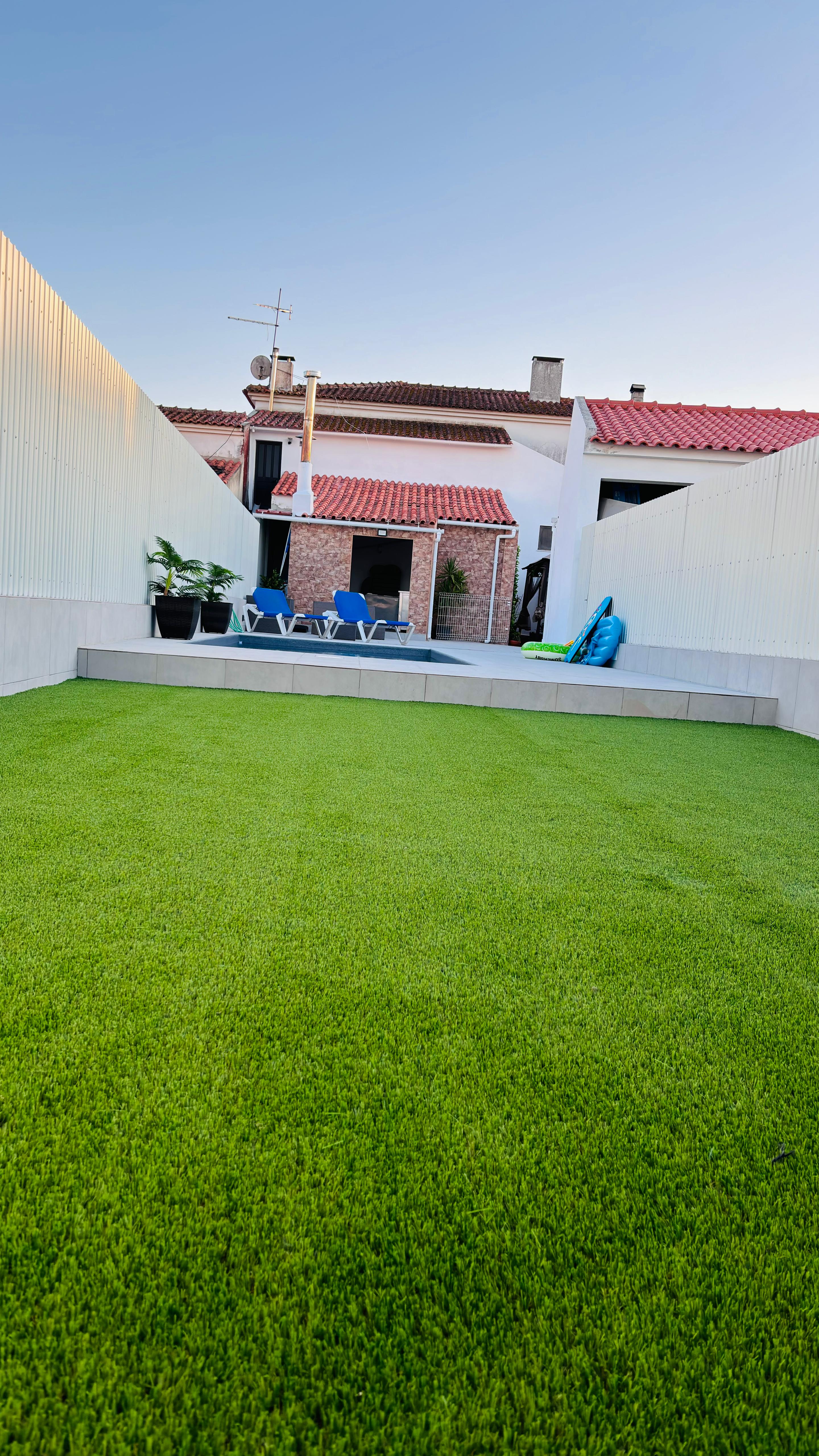 Resultado final da transformação do espaço com relva artificial de alta qualidade, apresentando um relvado uniforme e luxuriante, criando uma área verde perfeita para lazer