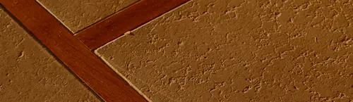 Verputzte Bodenplatten mit einer rotbraunen Holzfuge dazwischen