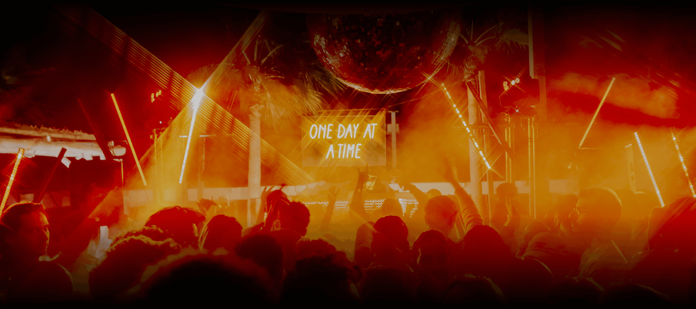 DJ mixing electronic music at ODAAT party with orange neon lights and motion blur on the dance floor.