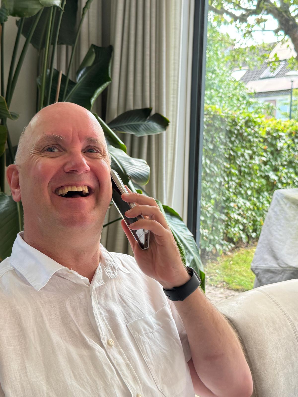 Rik, glimlachend aan de telefoon