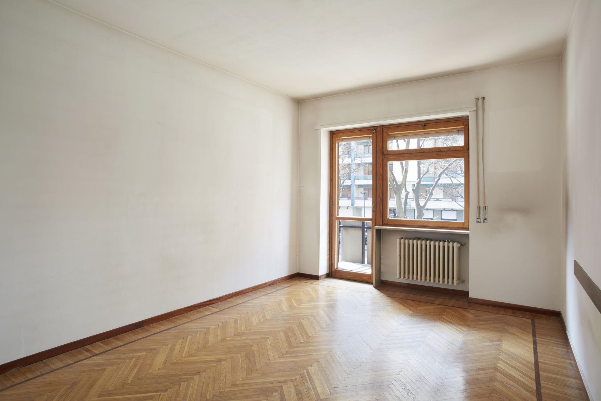 Large house with a wrap-around balcony overlooking a lit pool and deck at night.