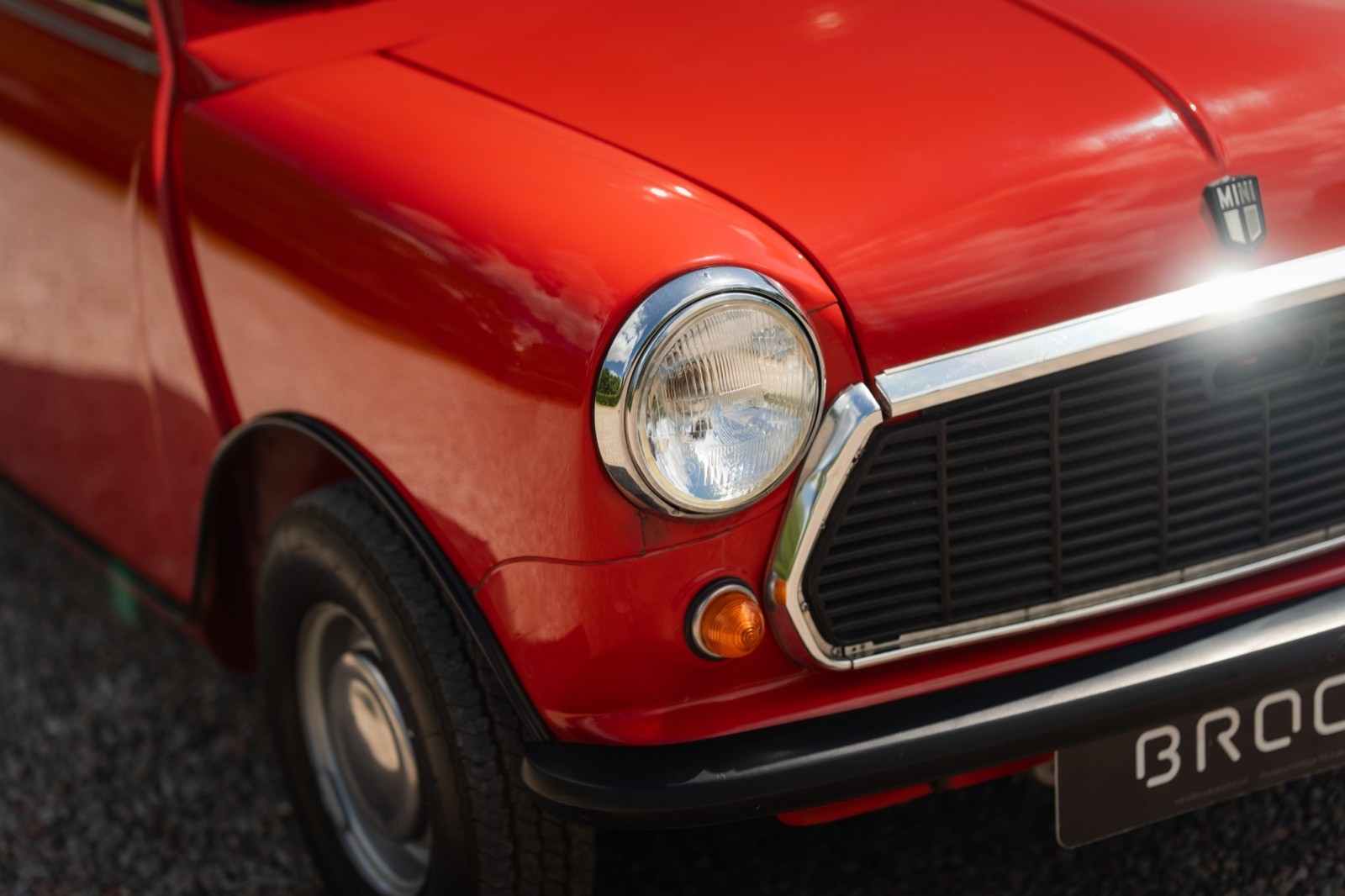 Close-up of a bright red vintage car, highlighting the front headlight and grill details.