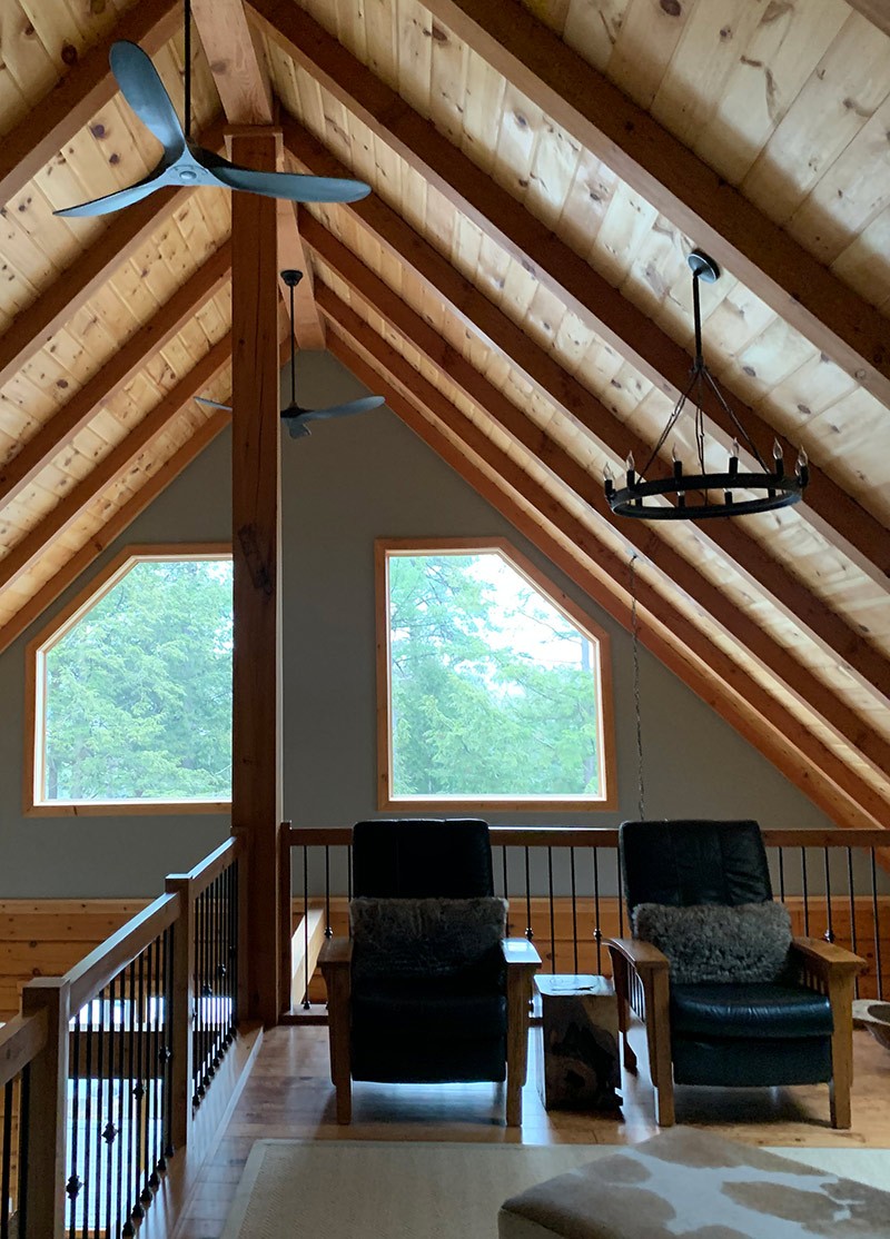 Vaulted ceiling loft with exposed beams and views of the forest.