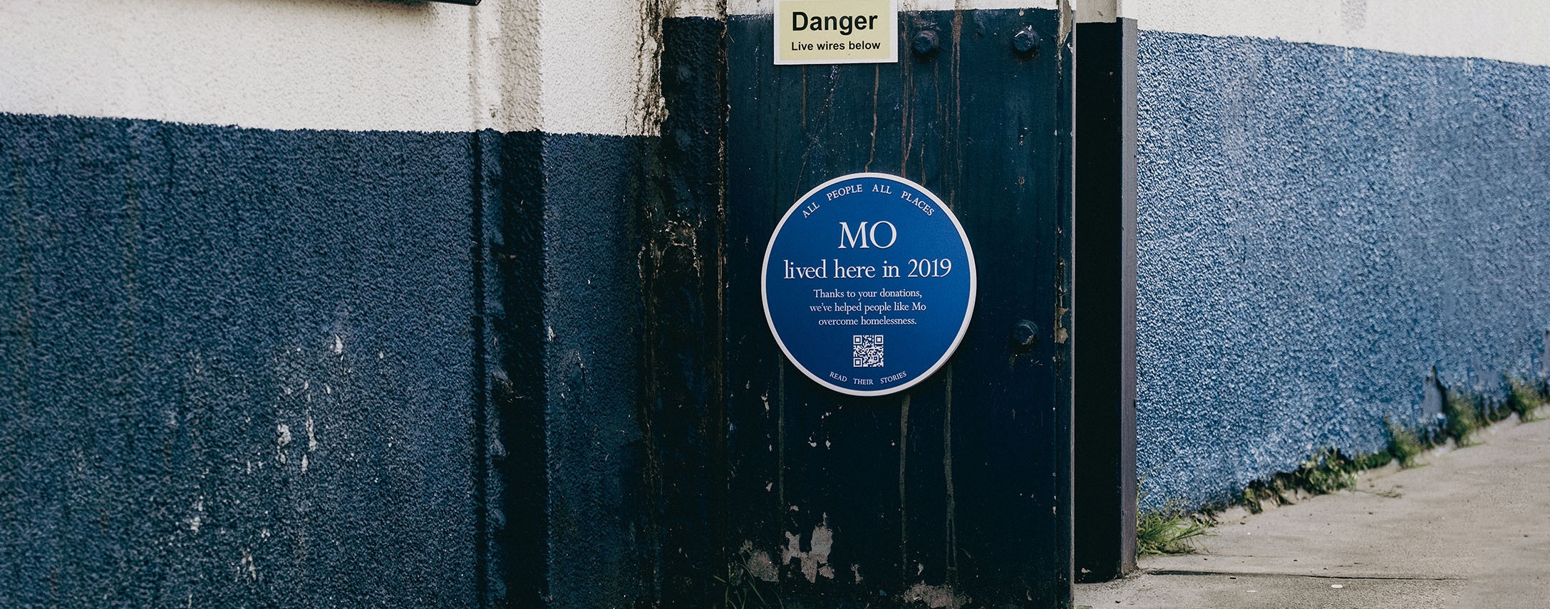 Blue plaque on a wall outside a factory on the street