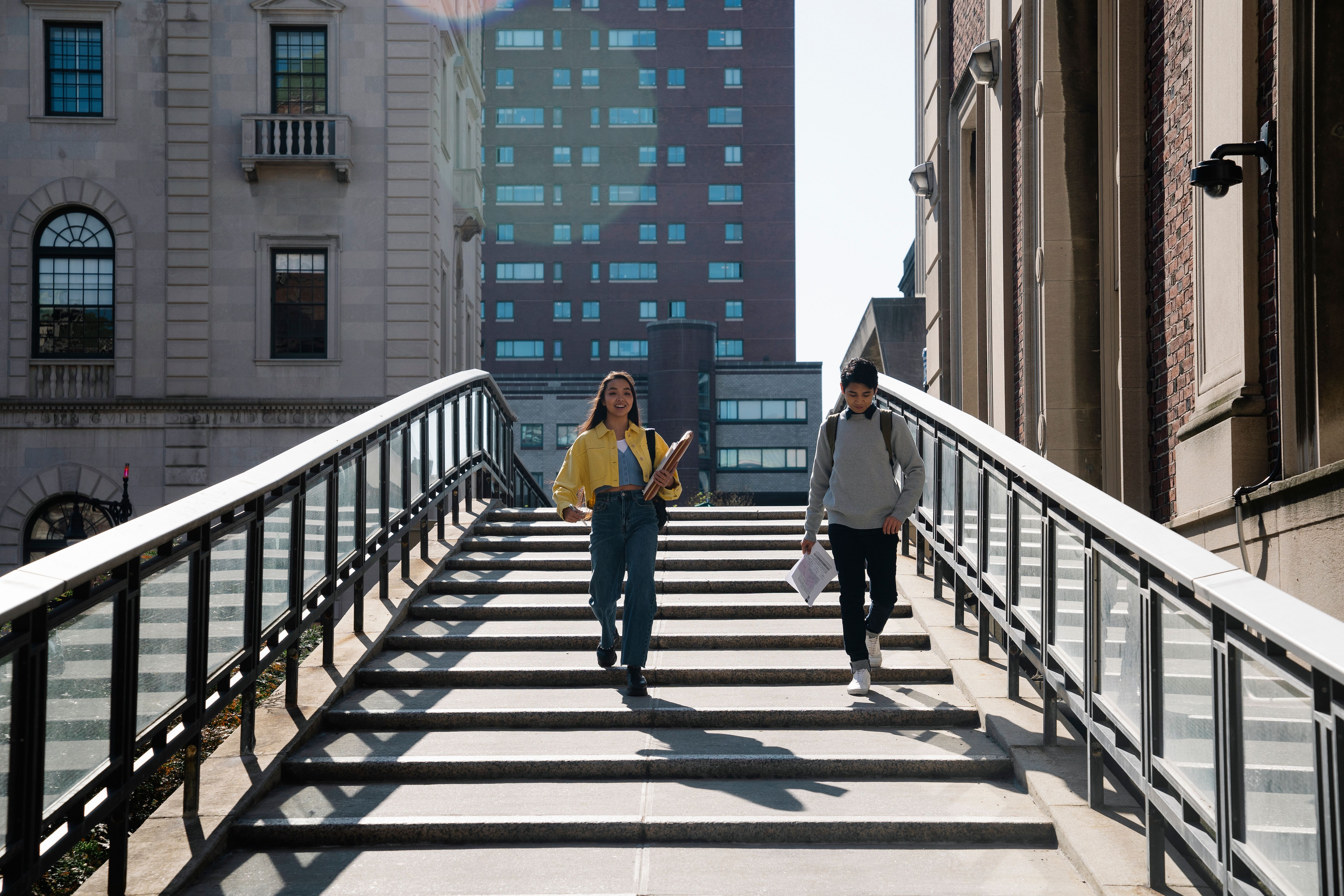 two-young-adults-walking-down-university-steps-in-an-urban-setting,-holding-note - george-pak (pexels)