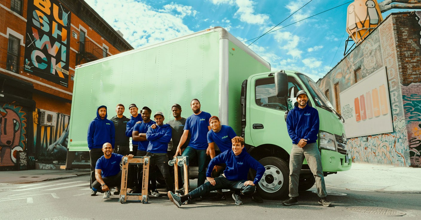 A large group of a moving company workers posing in front of a truck.
