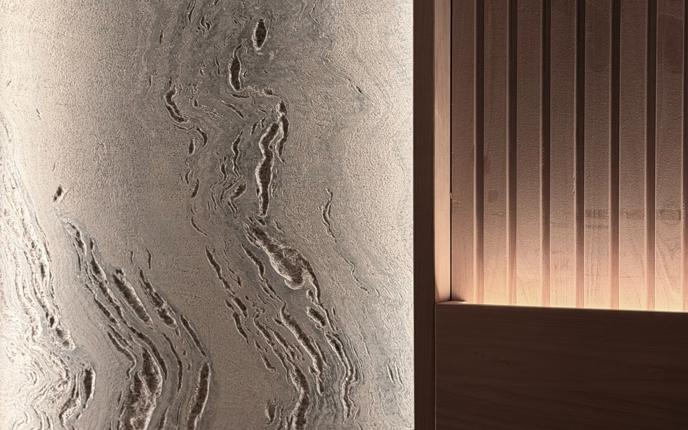 A carved stone wall beside slatted wood