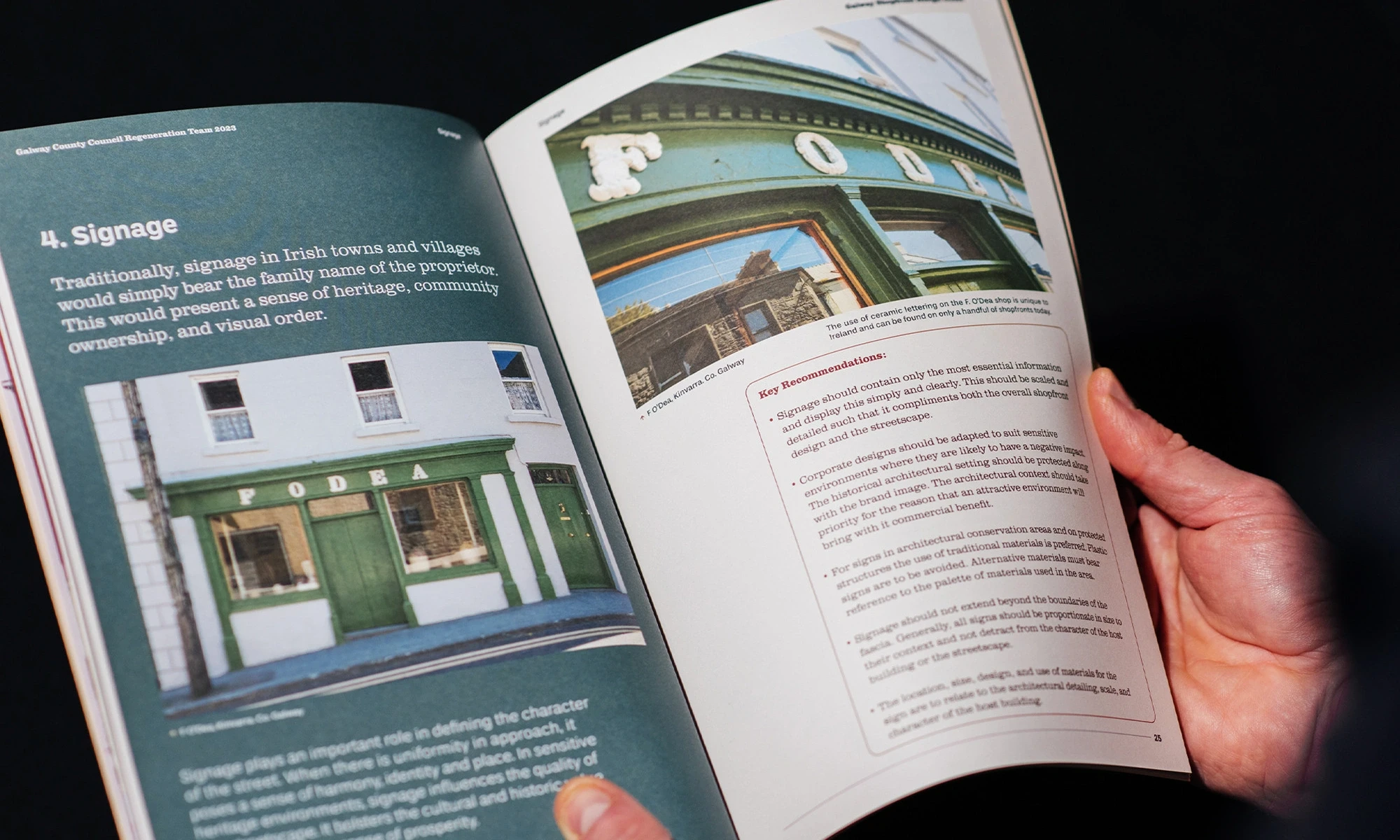 a man holding one of the guides showing some interior pages with photos of shopfronts