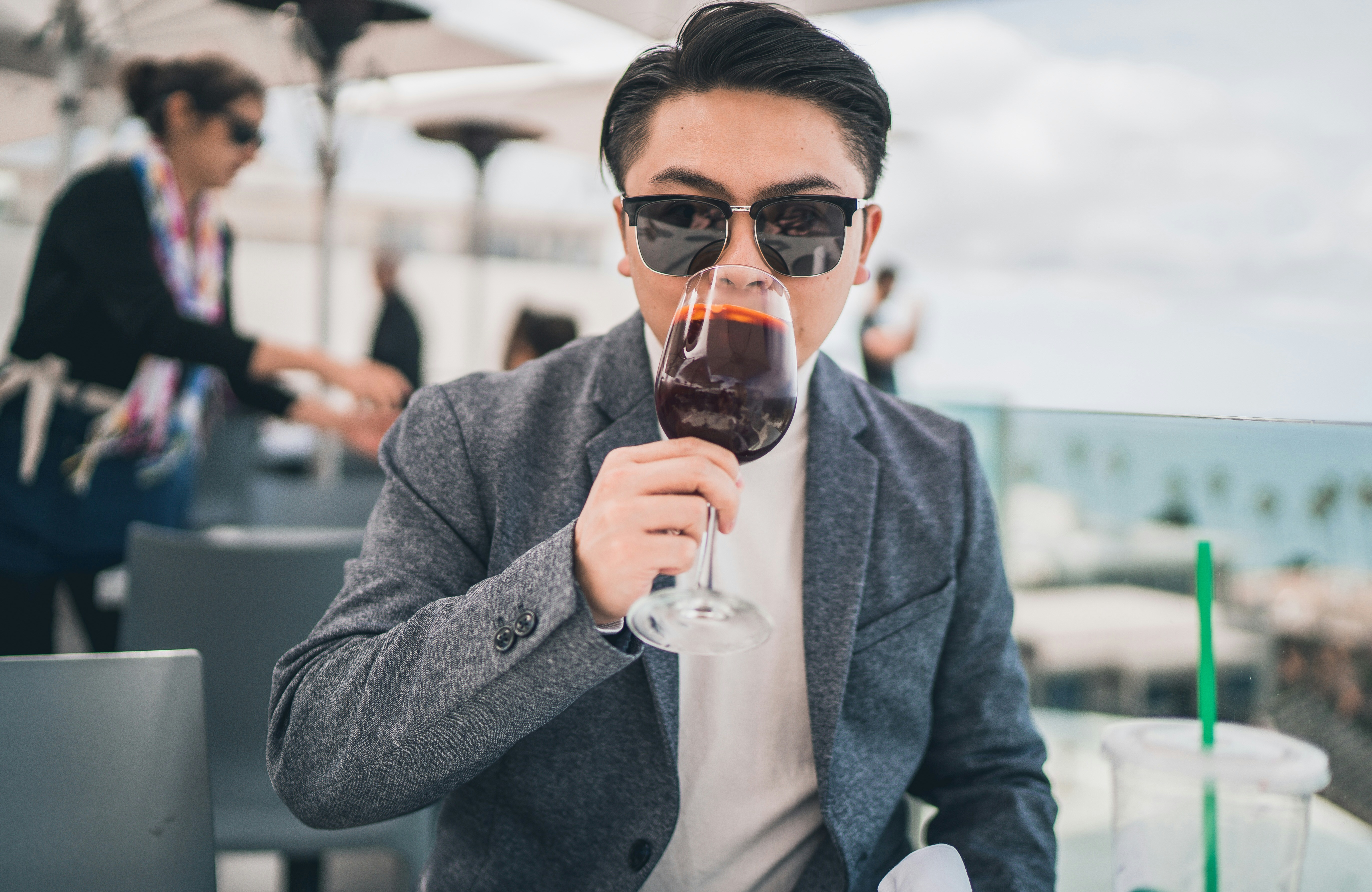 man in gray coat holding clear drinking glass