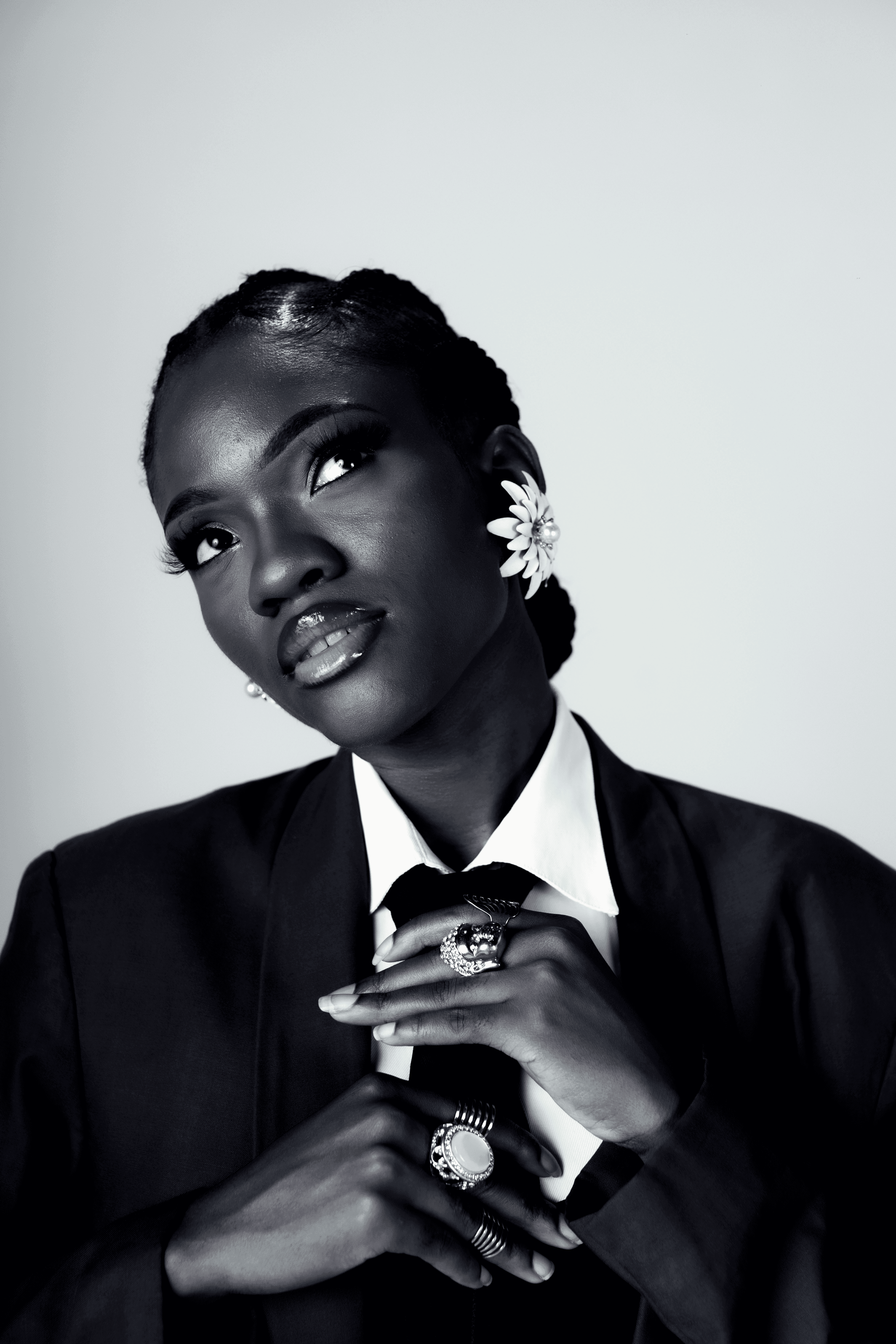 Woman in suit adjusts tie with ornate rings