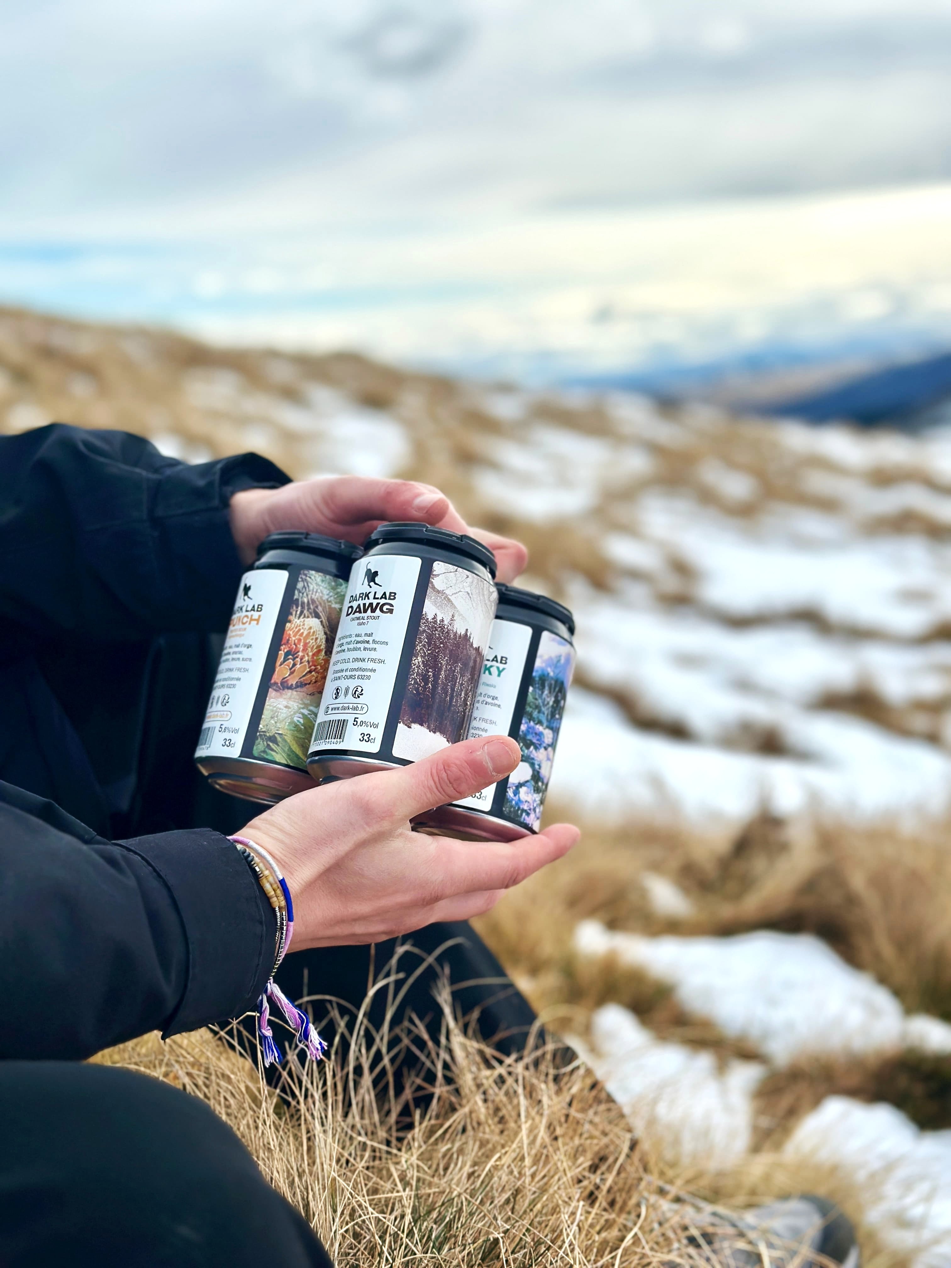 mains tenant un pack de 4 canettes dans la nature