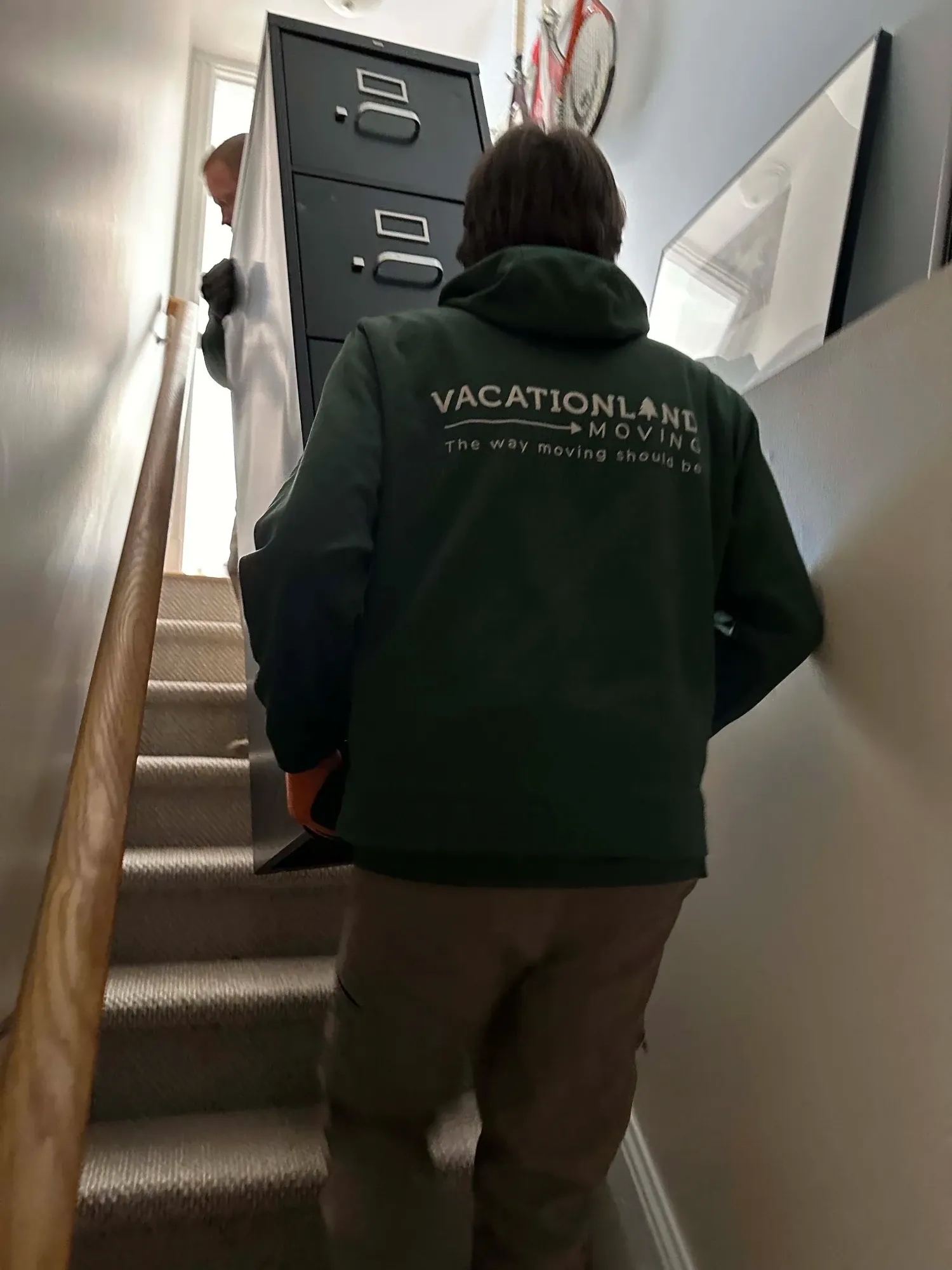 The crew carrying a filing cabinet up a narrow staircase