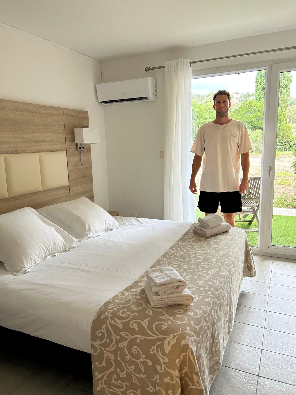 a man next to a bed doing housekeeping