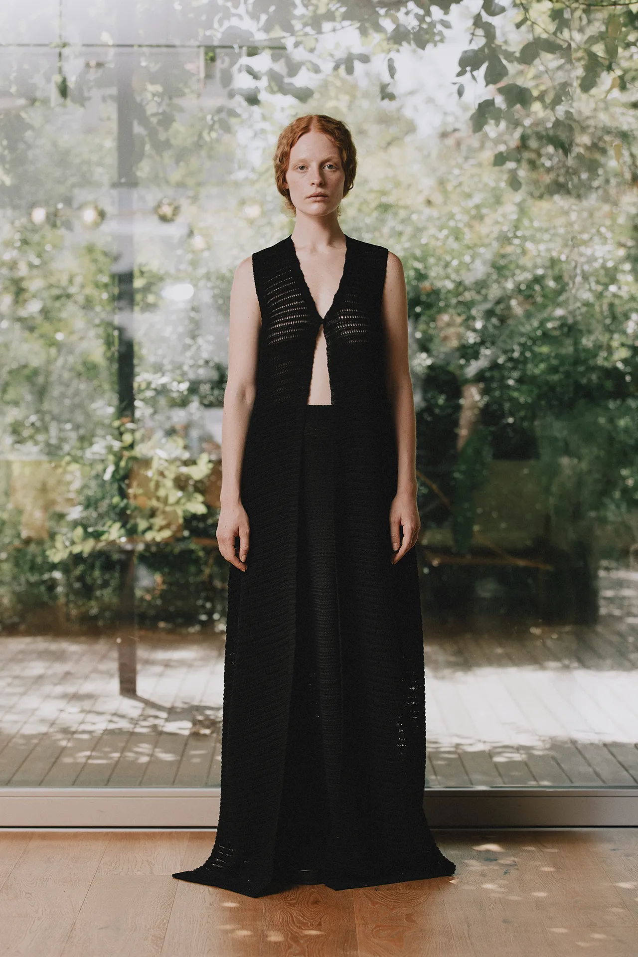 Annapurna SS26 collection black open-knit sleeveless long cardigan paired with matching black trousers.