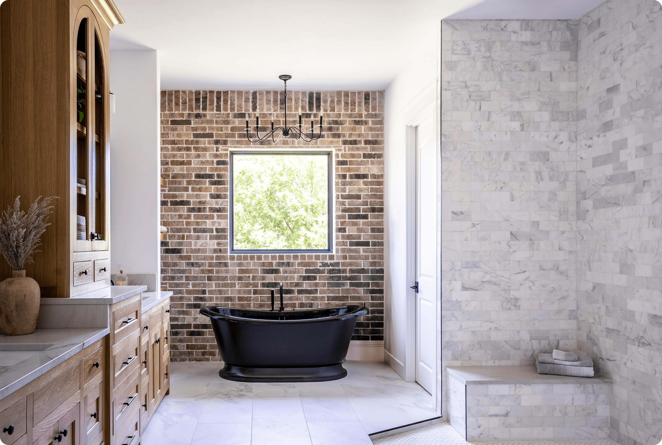 Luxurious modern bathroom featuring exposed brick accent wall, freestanding black bathtub, and marble-tiled walk-in shower